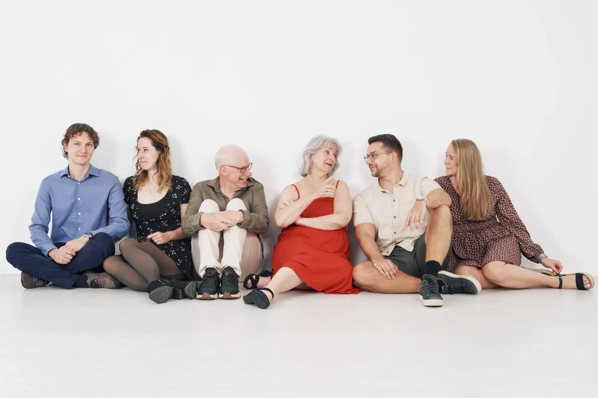Grote familie zit op een rij op de grond in de witte studio
