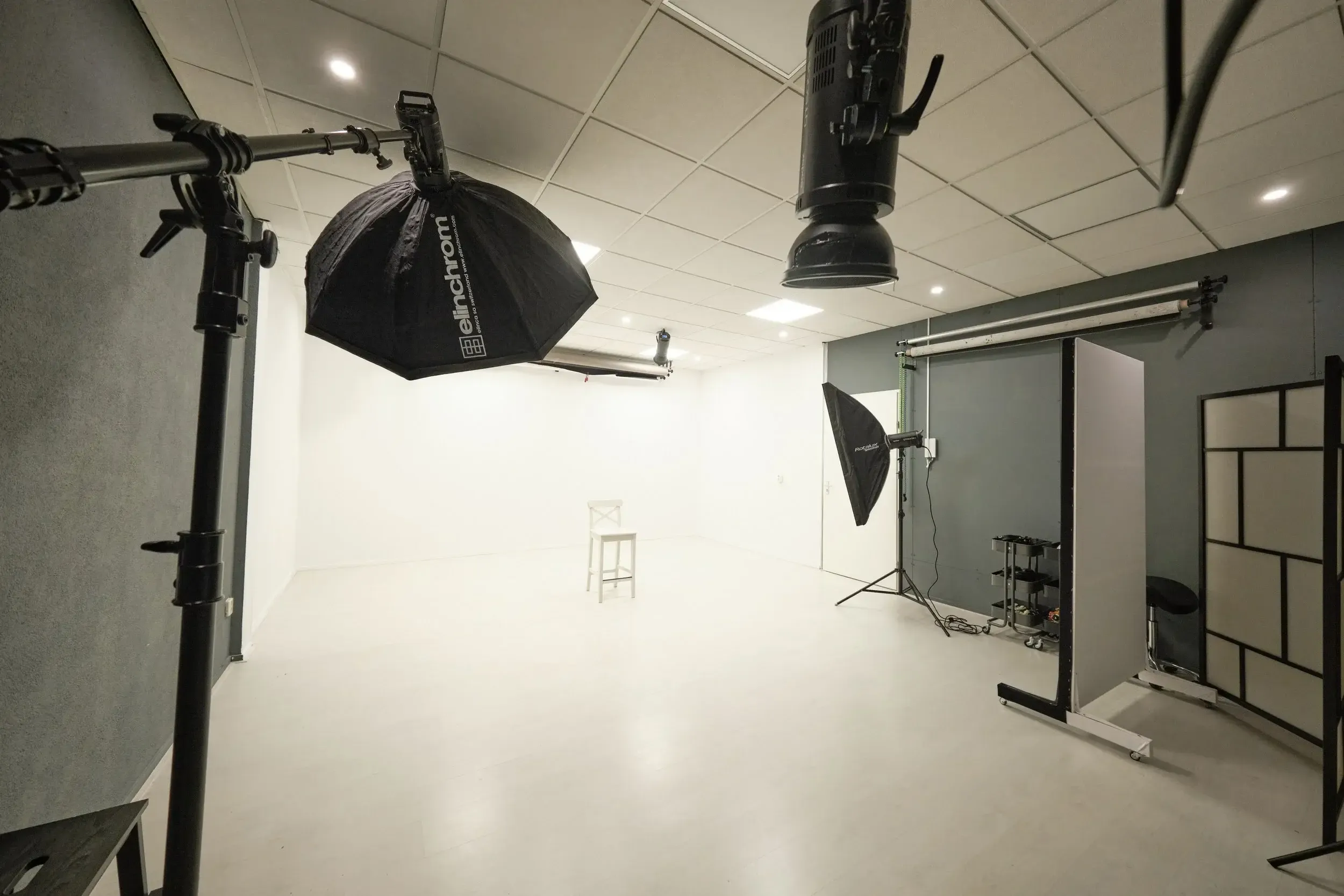 Fotostudio met professionele belichting en een witte achtergrond, inclusief statieven en apparatuur voor fotosessies.
