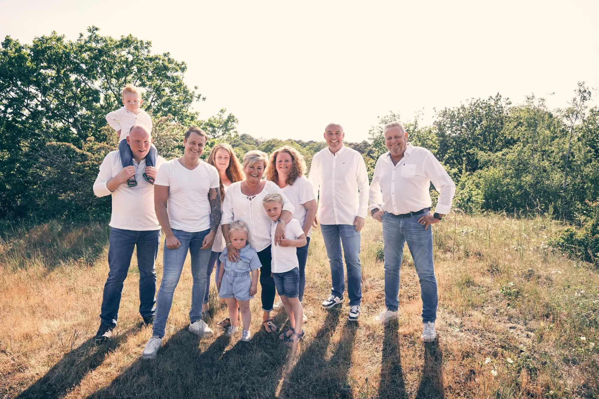 Twee gezinnen staan samen op een open duinvlakte met de lage zon in hun rug