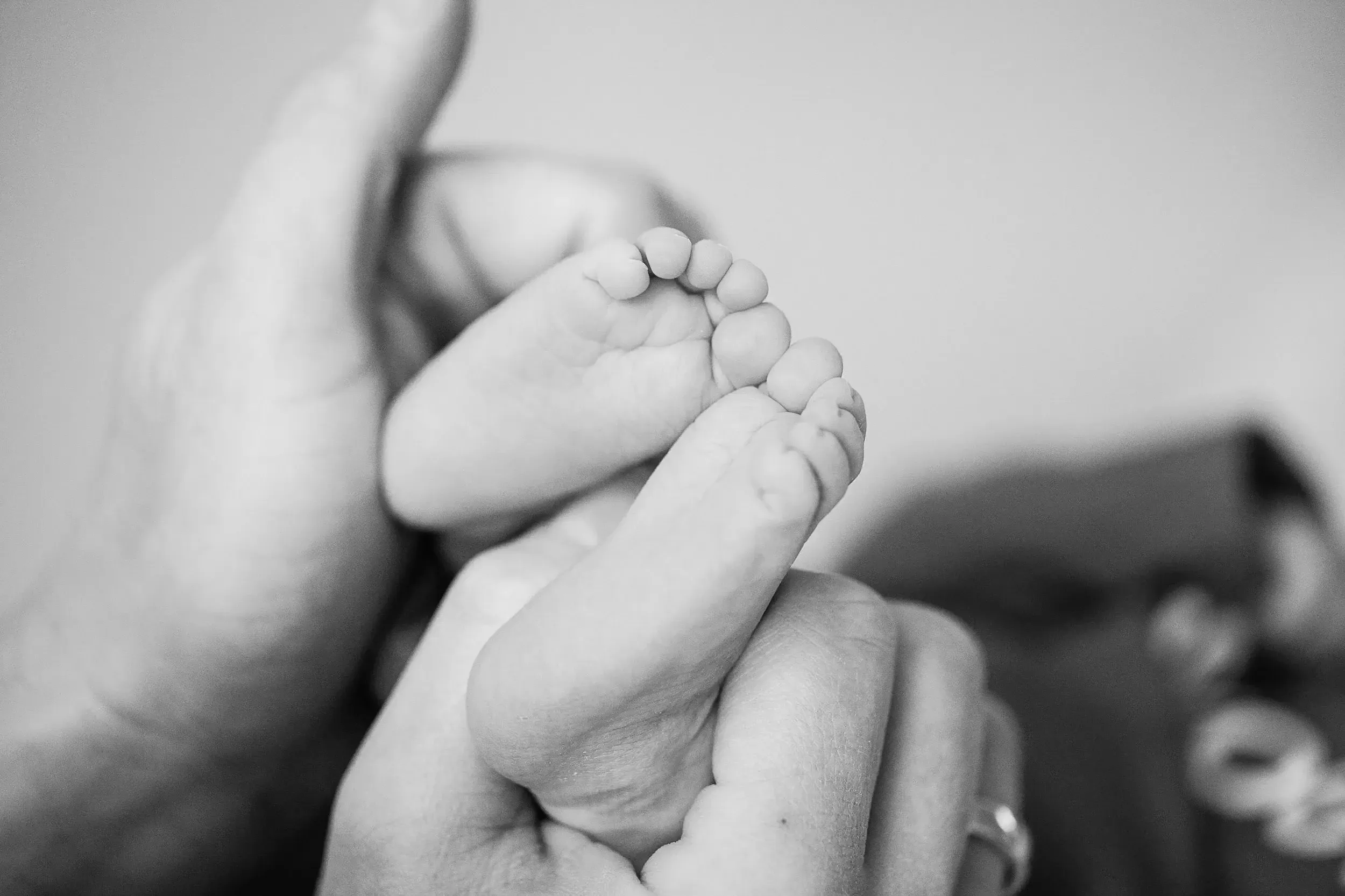 Een close-up van een babyhand die een volwassen vinger vasthoudt, zwart-wit foto.