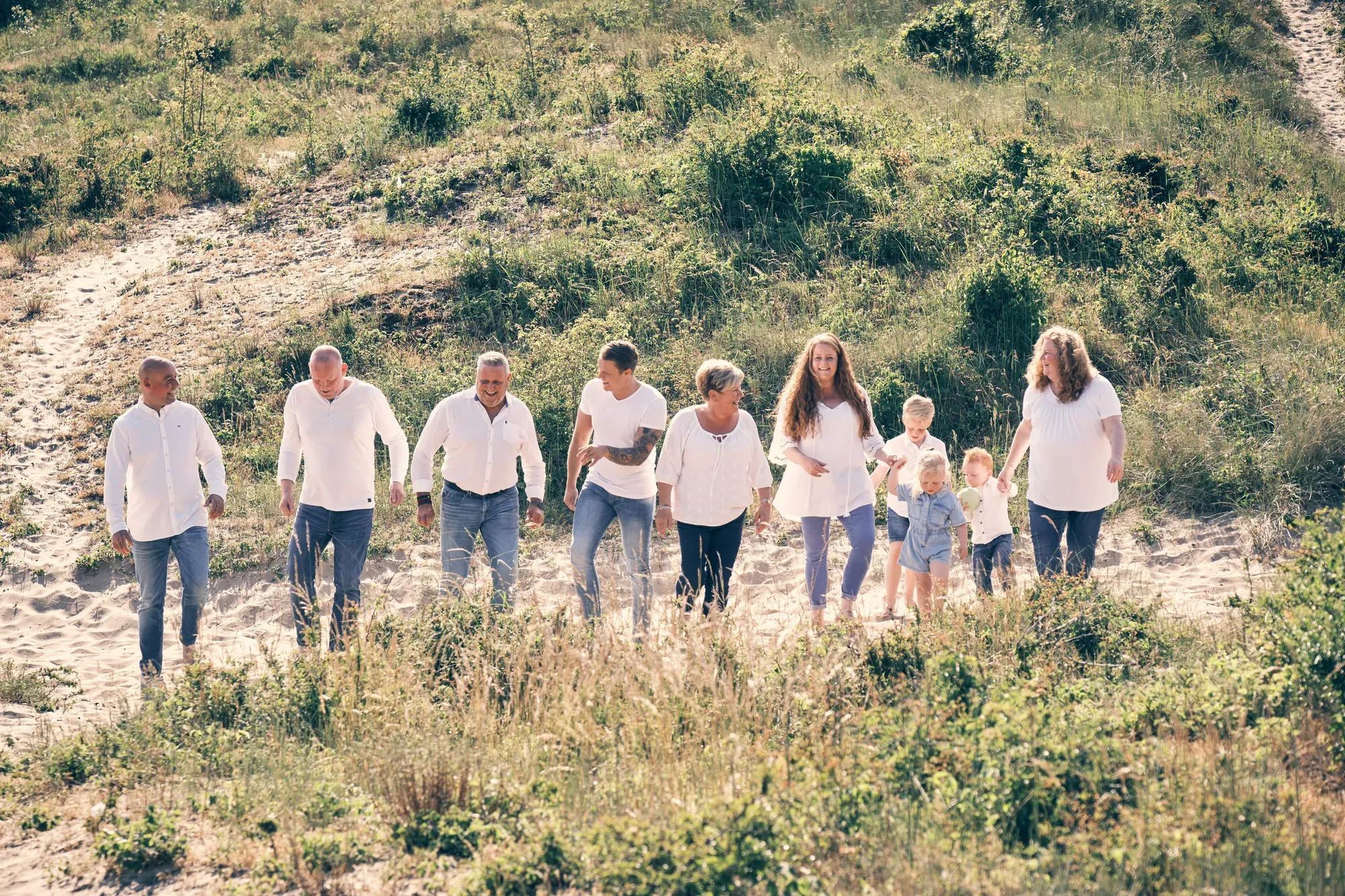 Familie loopt lachend samen over het duin in warm tegenlicht