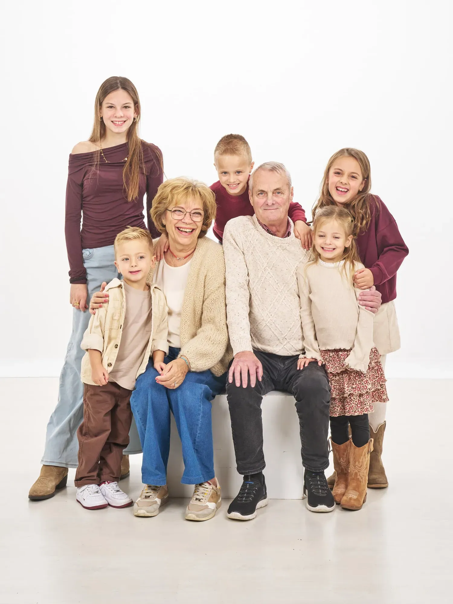 Familie zit en staat samen rond een bankje in de witte fotostudio