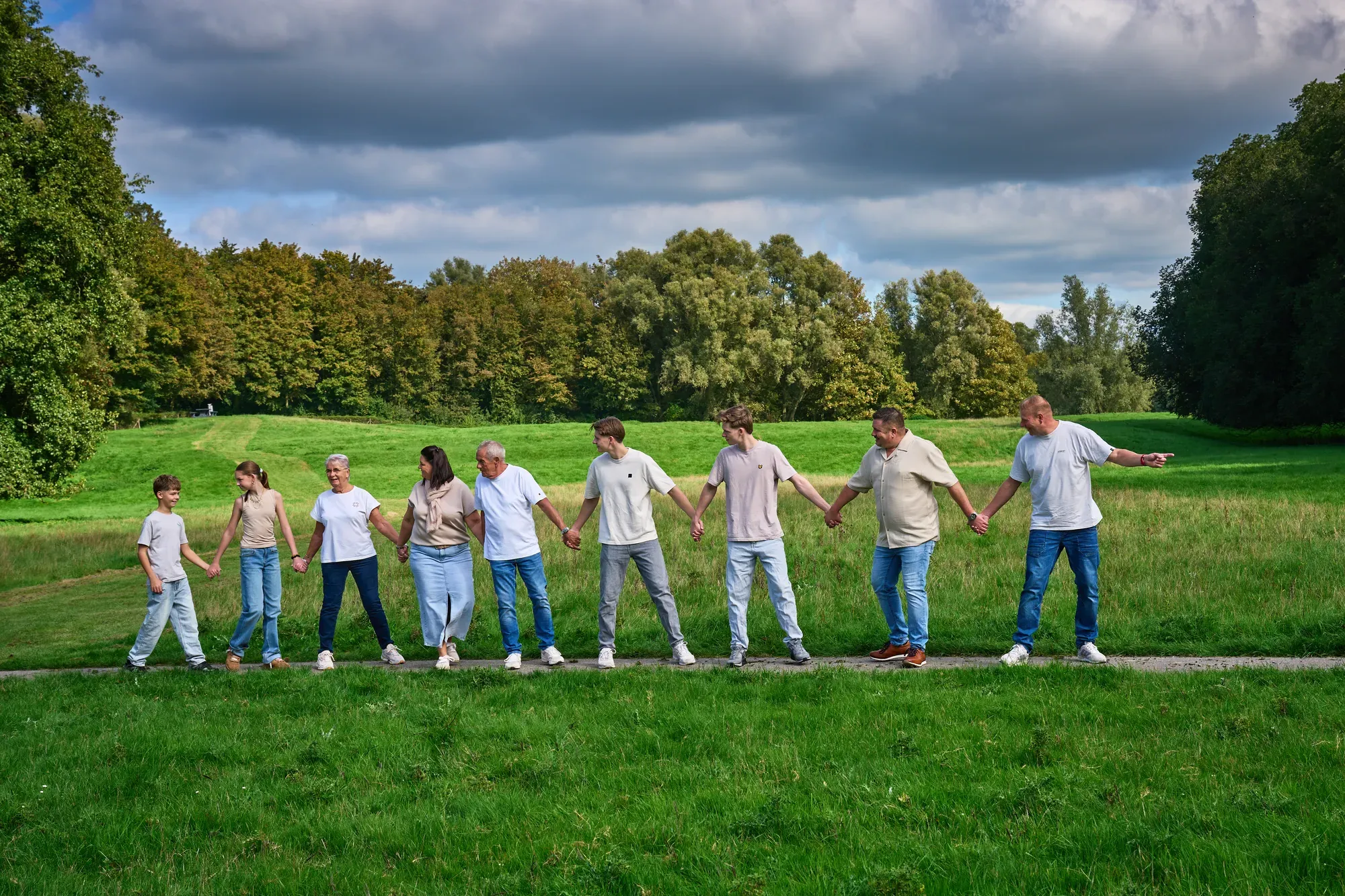 Grote familie staat hand in hand op een rij in het gras