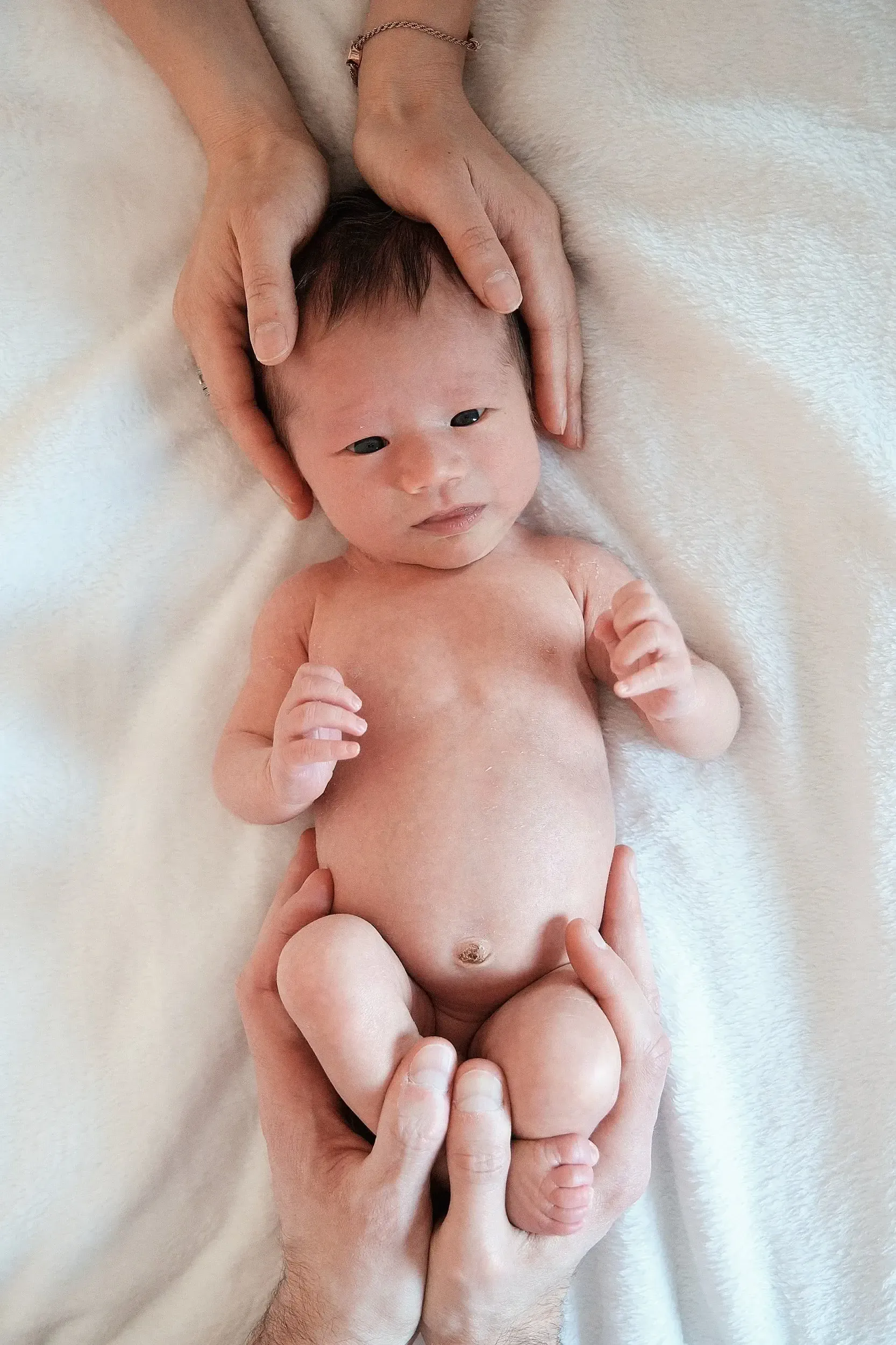 De handen van de ouders op deze foto verbinden hen met de baby.