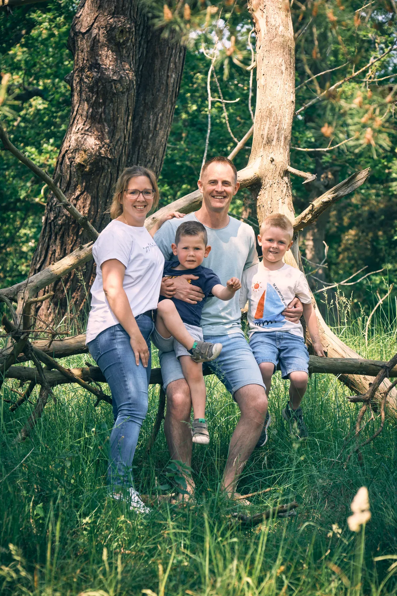 Gezin zit samen op een omgevallen boom in het bos