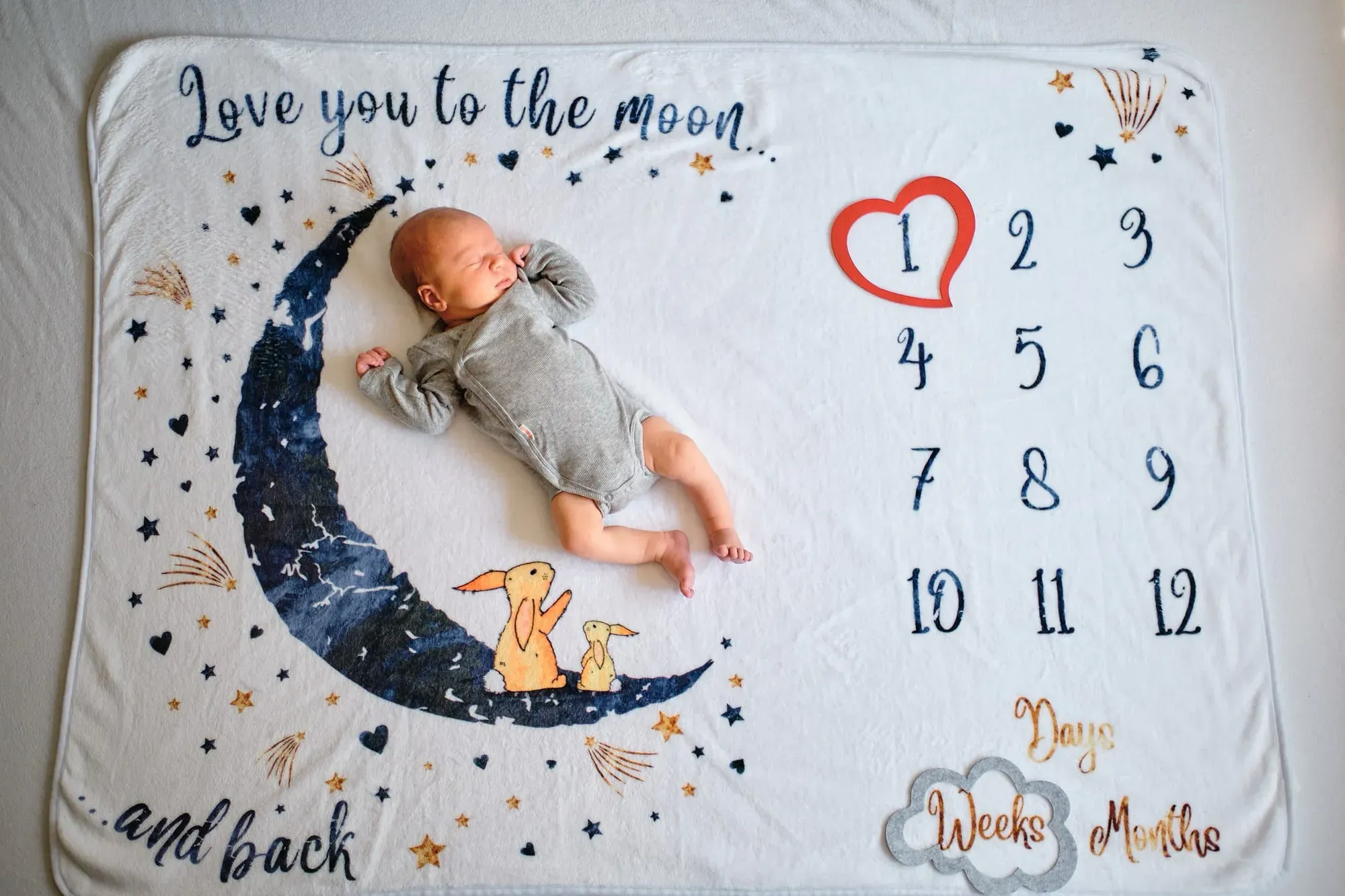 Baby ligt op een mijlpaaldeken met maan en sterren