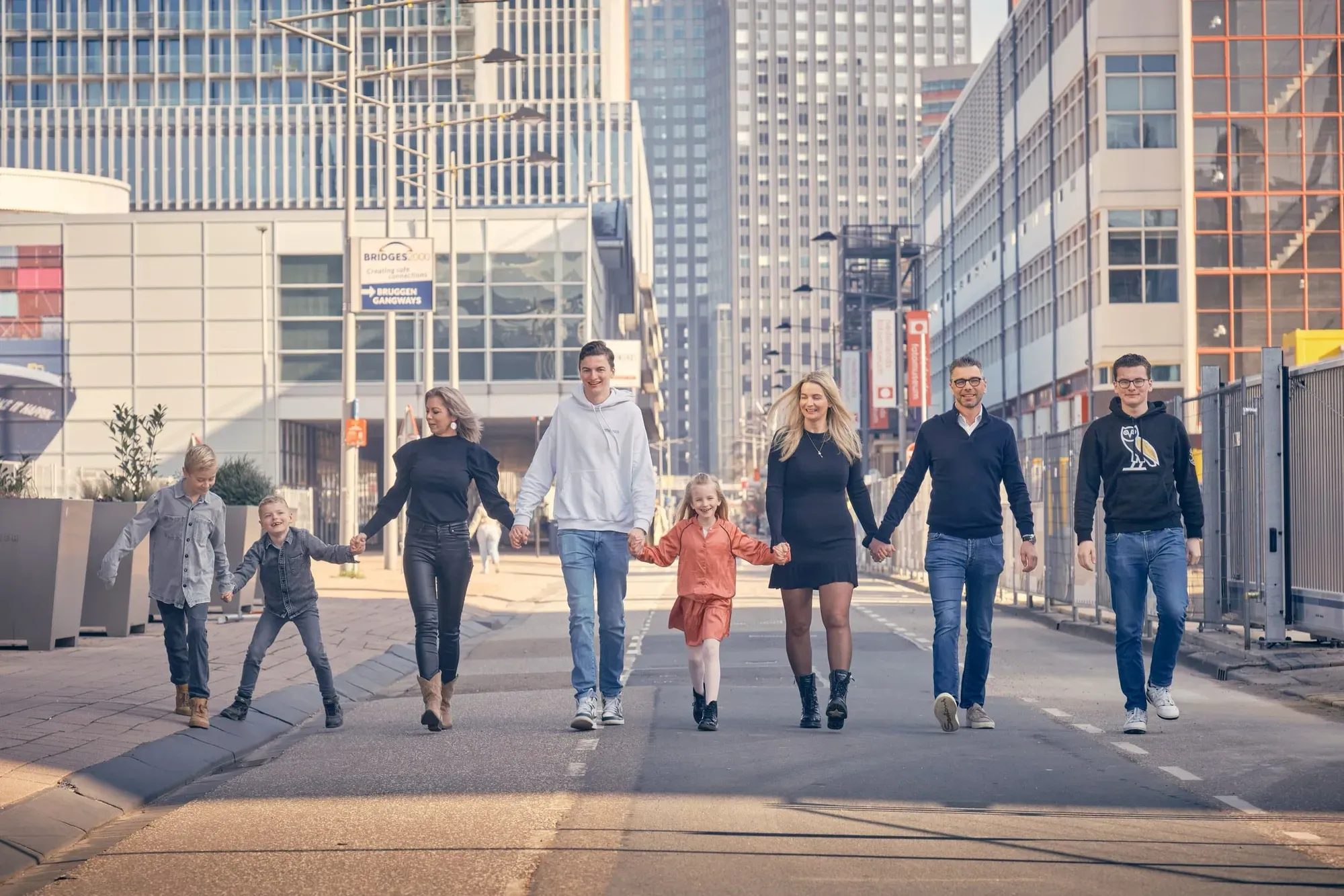 Familie loopt hand in hand over een straat tussen moderne hoogbouw