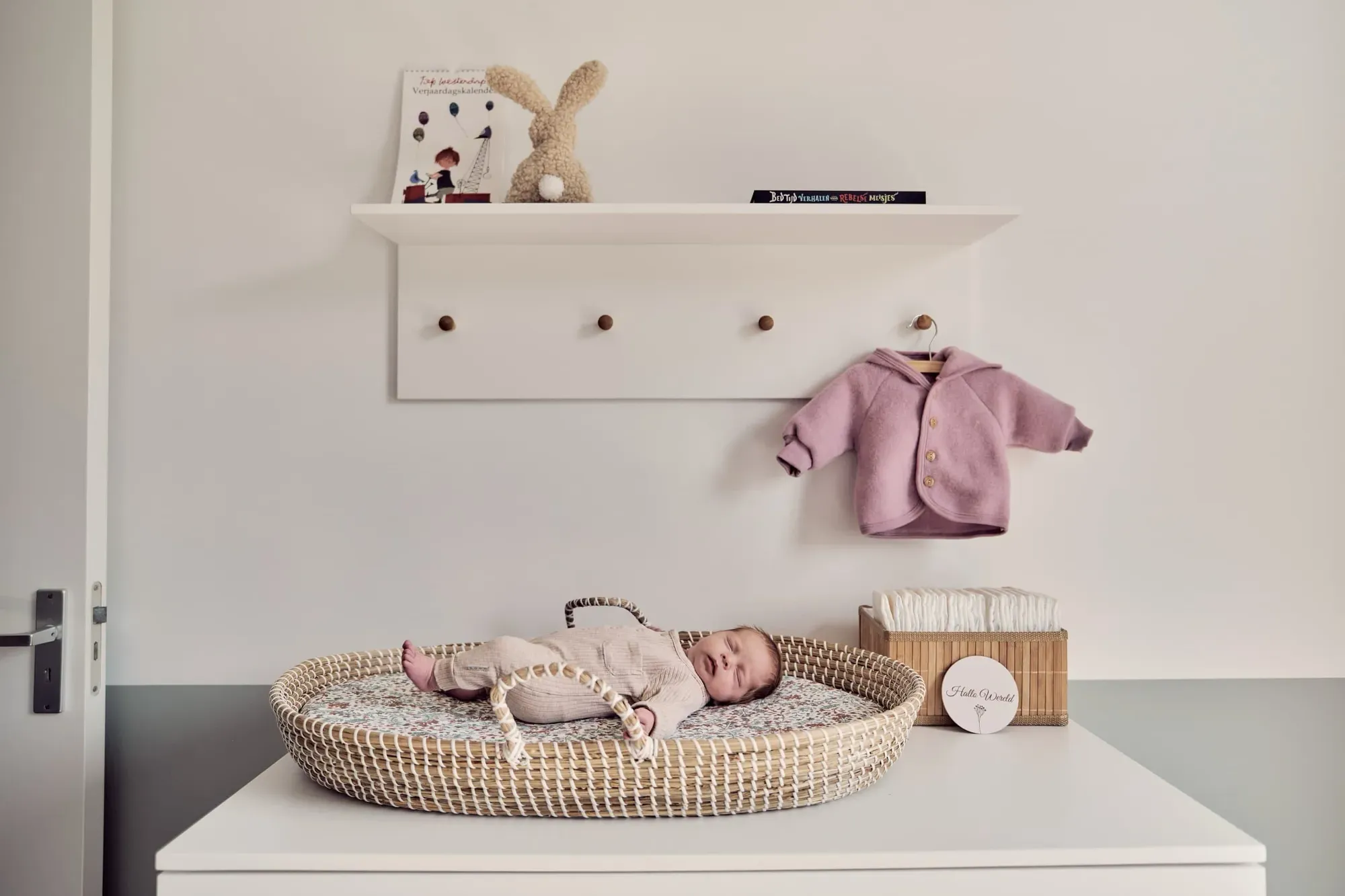 De babykamer met een wiegje en kleine kledingstukjes aan de muur