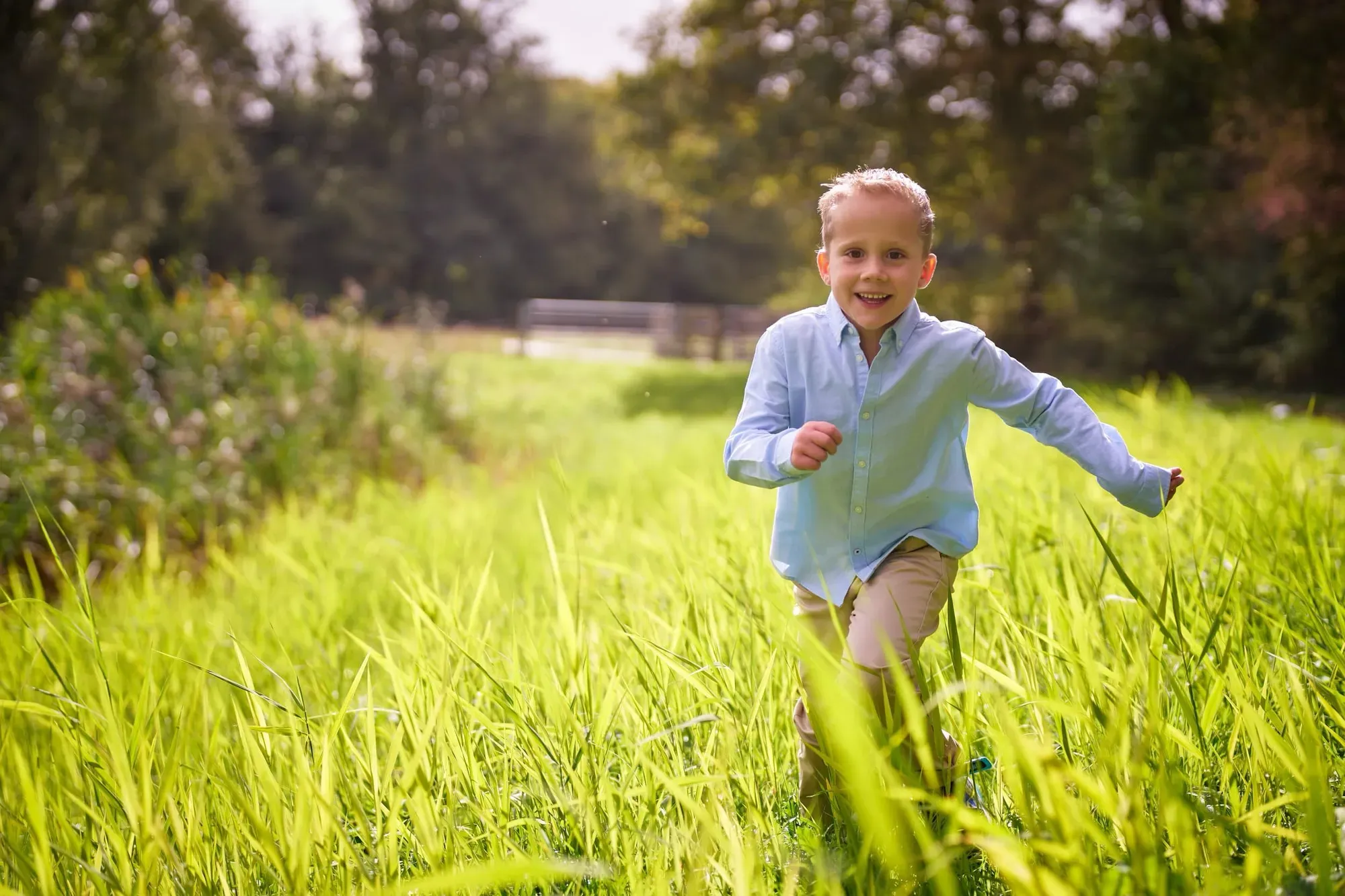 Kind rent lachend door het hoge gras