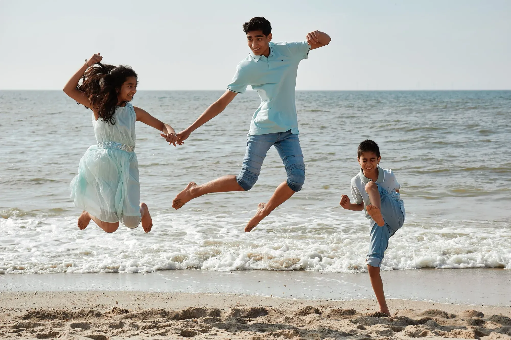 Kinderen springen hand in hand in de branding