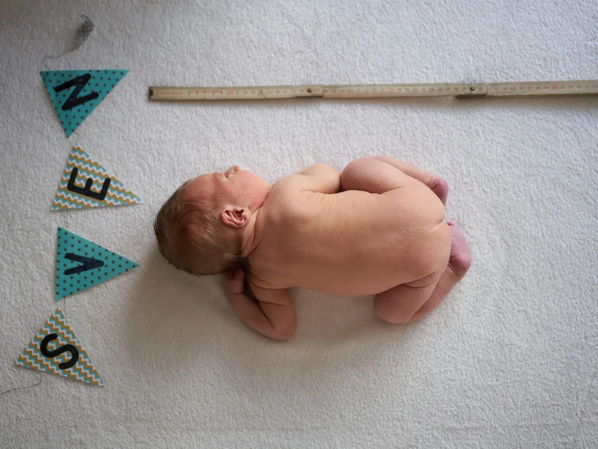 Pasgeboren baby ligt onder een slinger met de naam