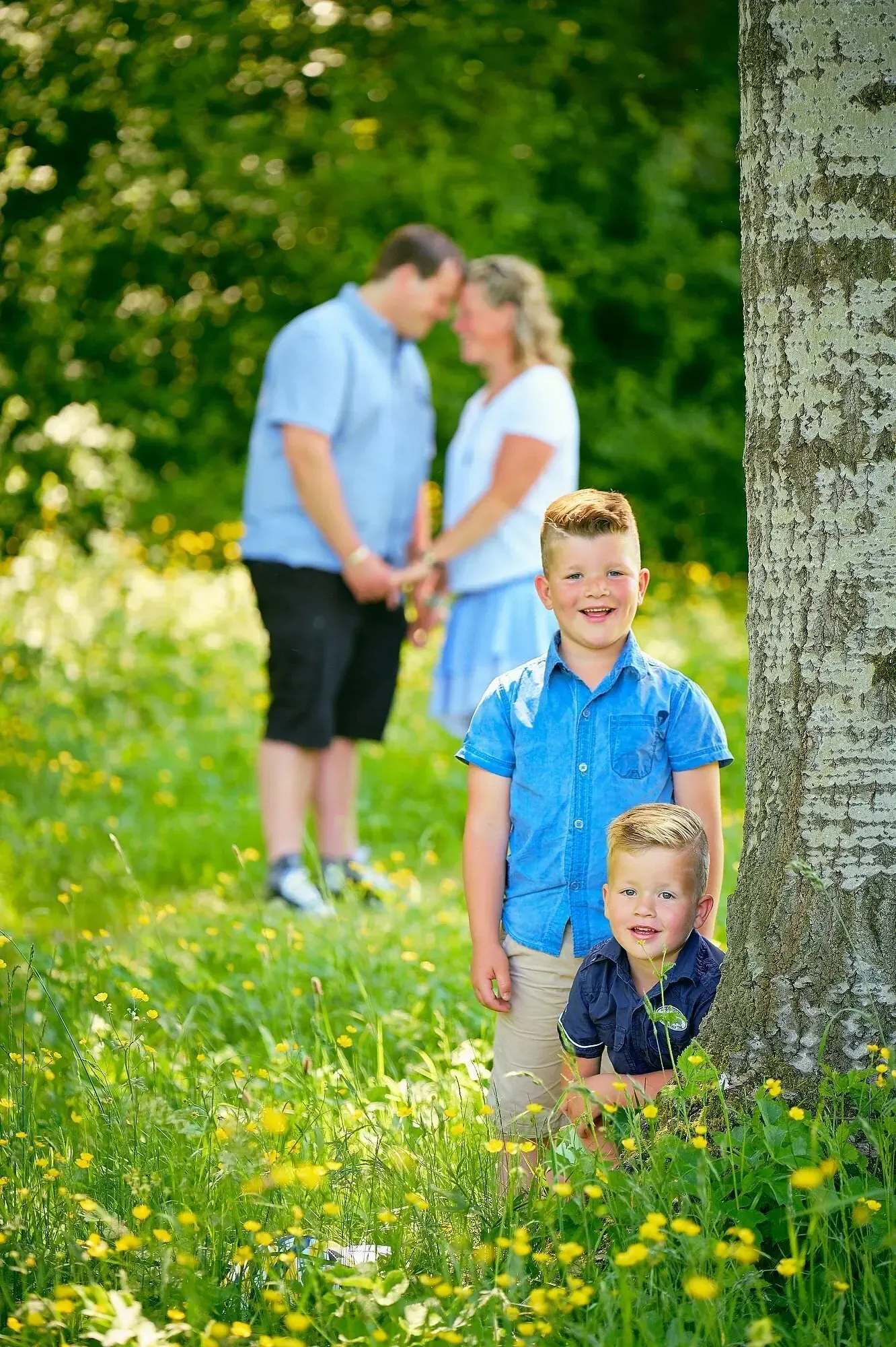 Het gezin staat onder een aantal grote bomen en er komt wat licht van achter waardoor je mooi zacht licht krijgt op de gezichten van de kinderen.