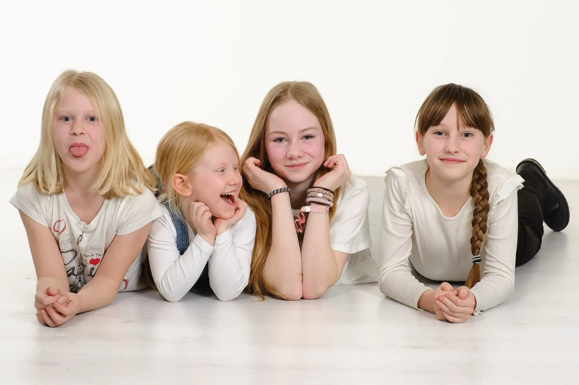 Kinderen liggen lachend naast elkaar op de grond in de witte studio