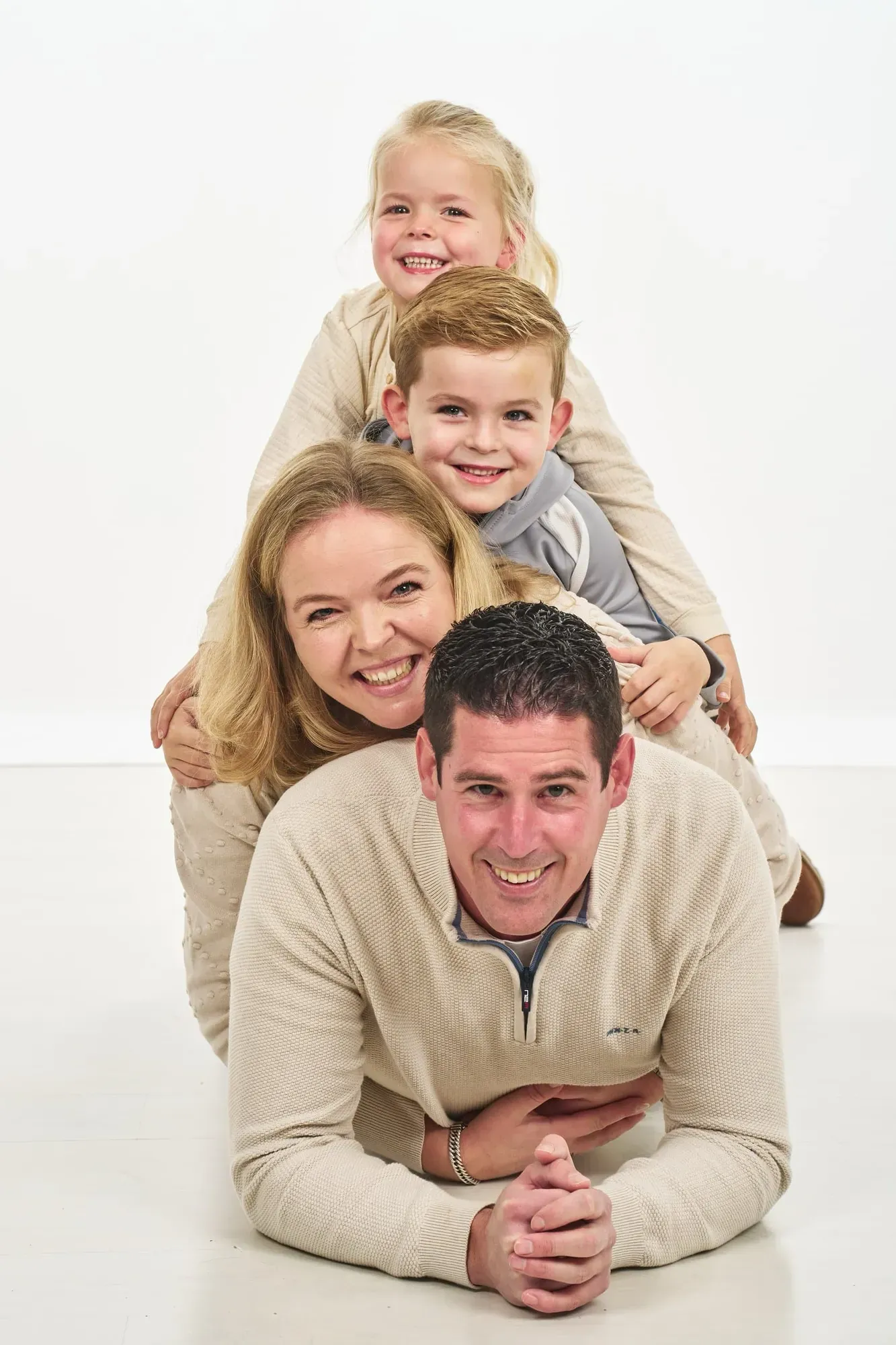 Gezin ligt op de grond, de kinderen op de rug van hun ouders