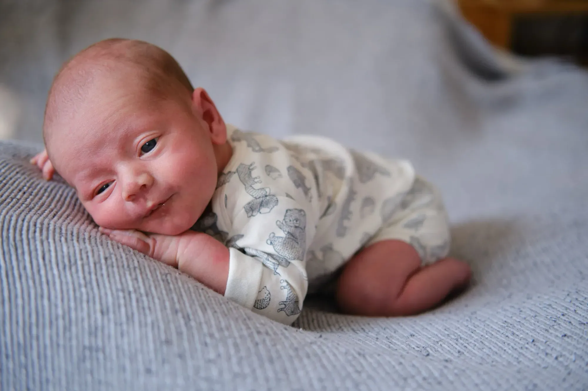 Pasgeboren baby ligt op een deken en kijkt even op