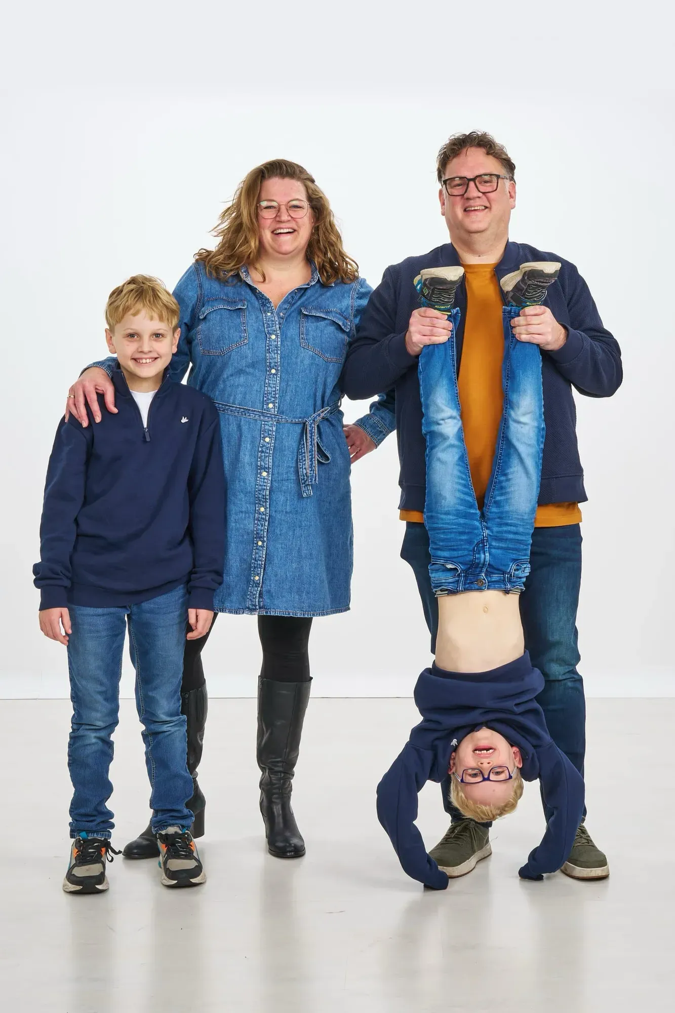 Gezin staat naast elkaar terwijl vader een kind ondersteboven houdt