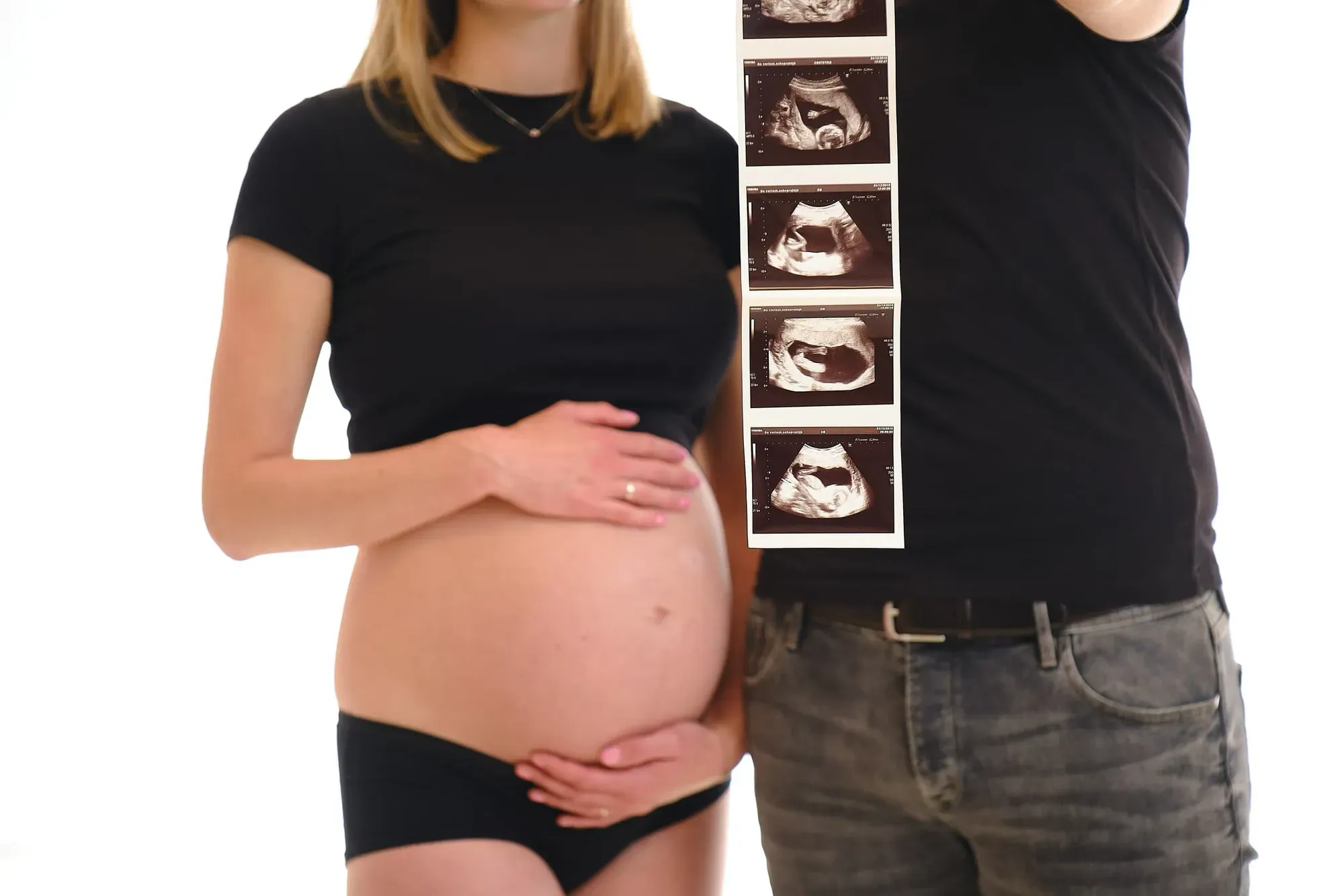 Stel in zwarte kleding met de buik bloot en een echo in de hand