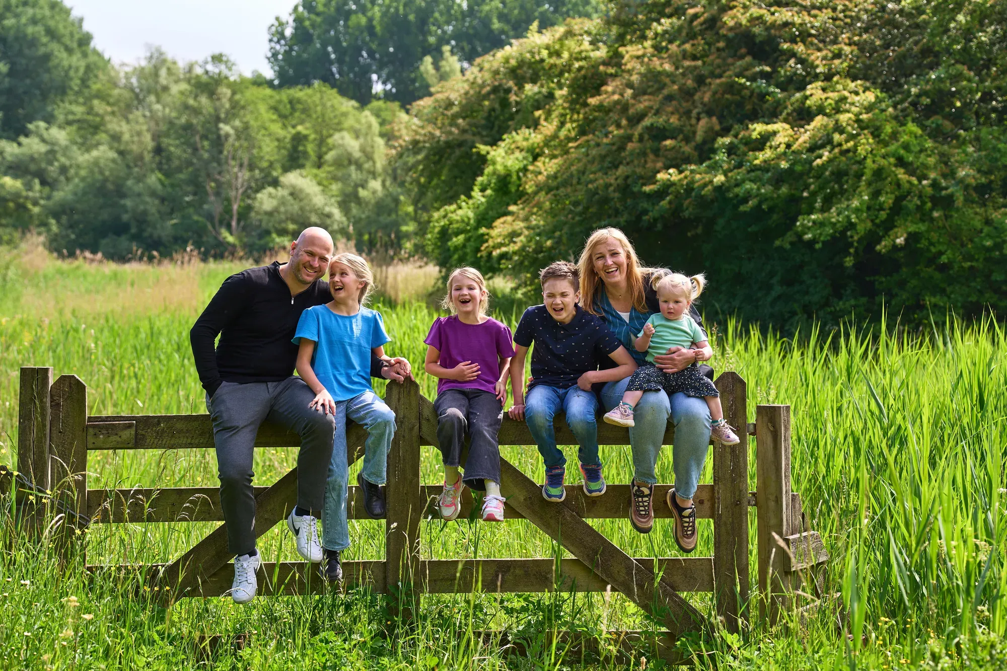 Gezin zit op een houten hek in het hoge gras van het Westerpark