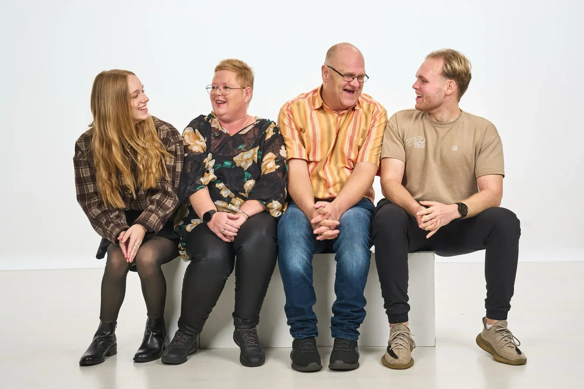 Familie zit naast elkaar op een witte bank in de studio