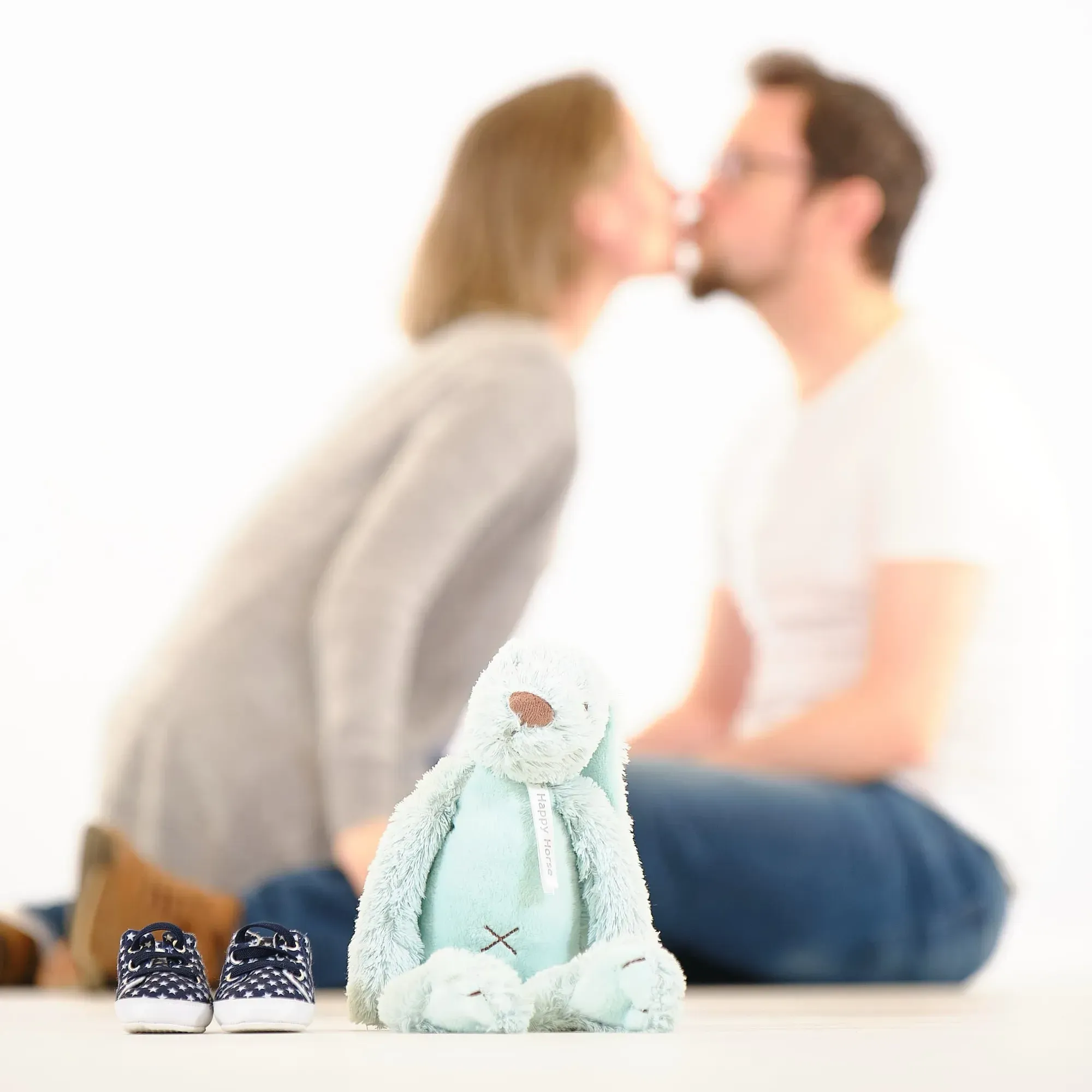 Stel kust elkaar met een knuffel en babyschoentjes op de voorgrond