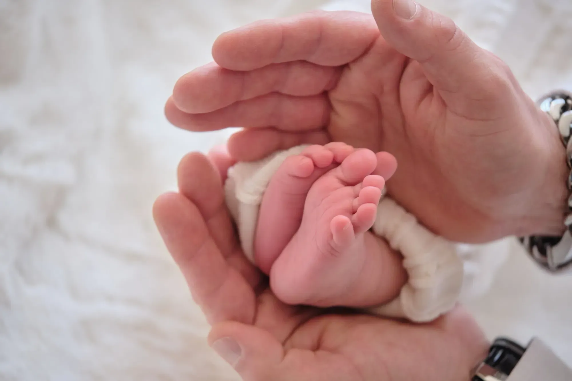 Voetjes van een pasgeboren baby in grote handen