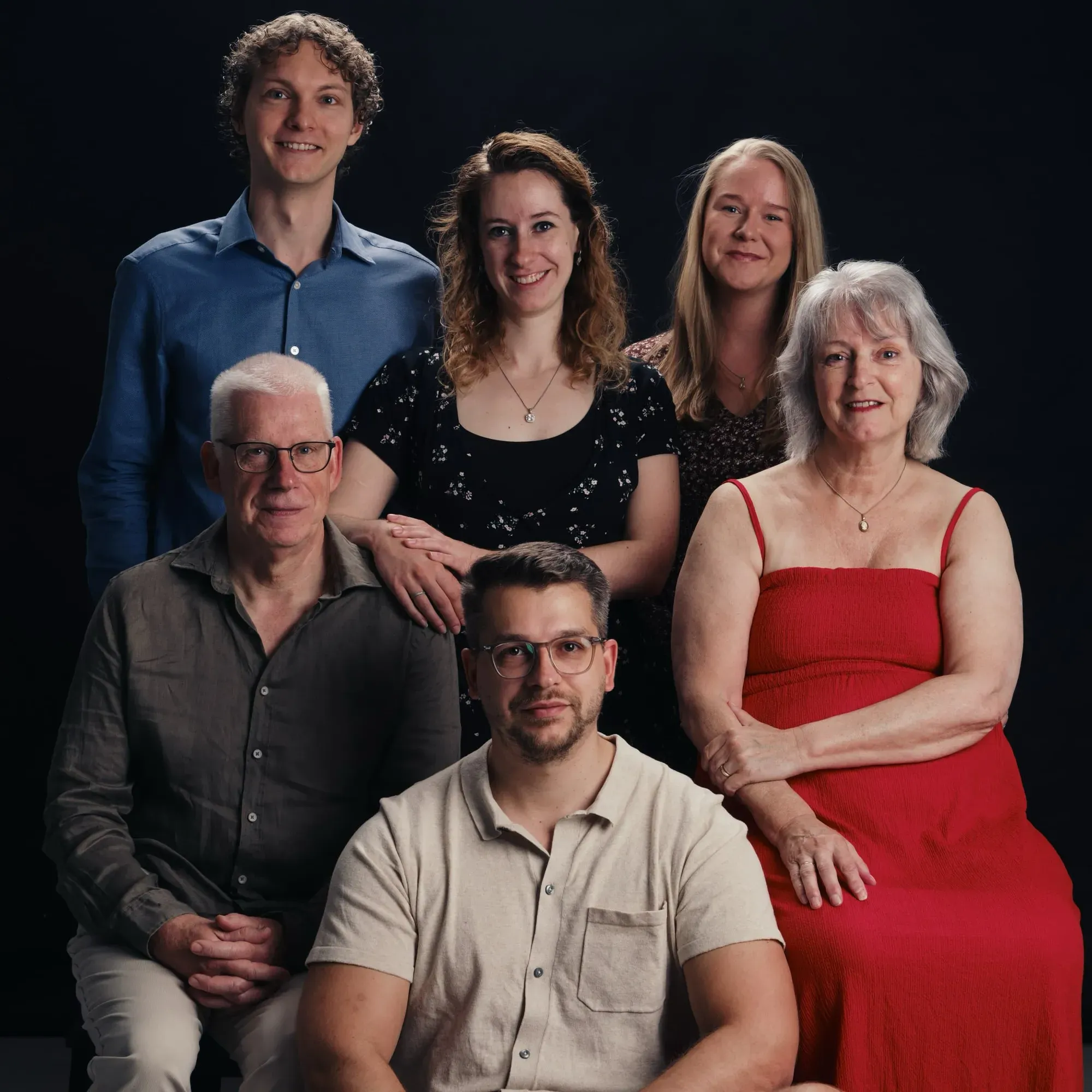 Familie van drie generaties poseert voor een zwarte achtergrond