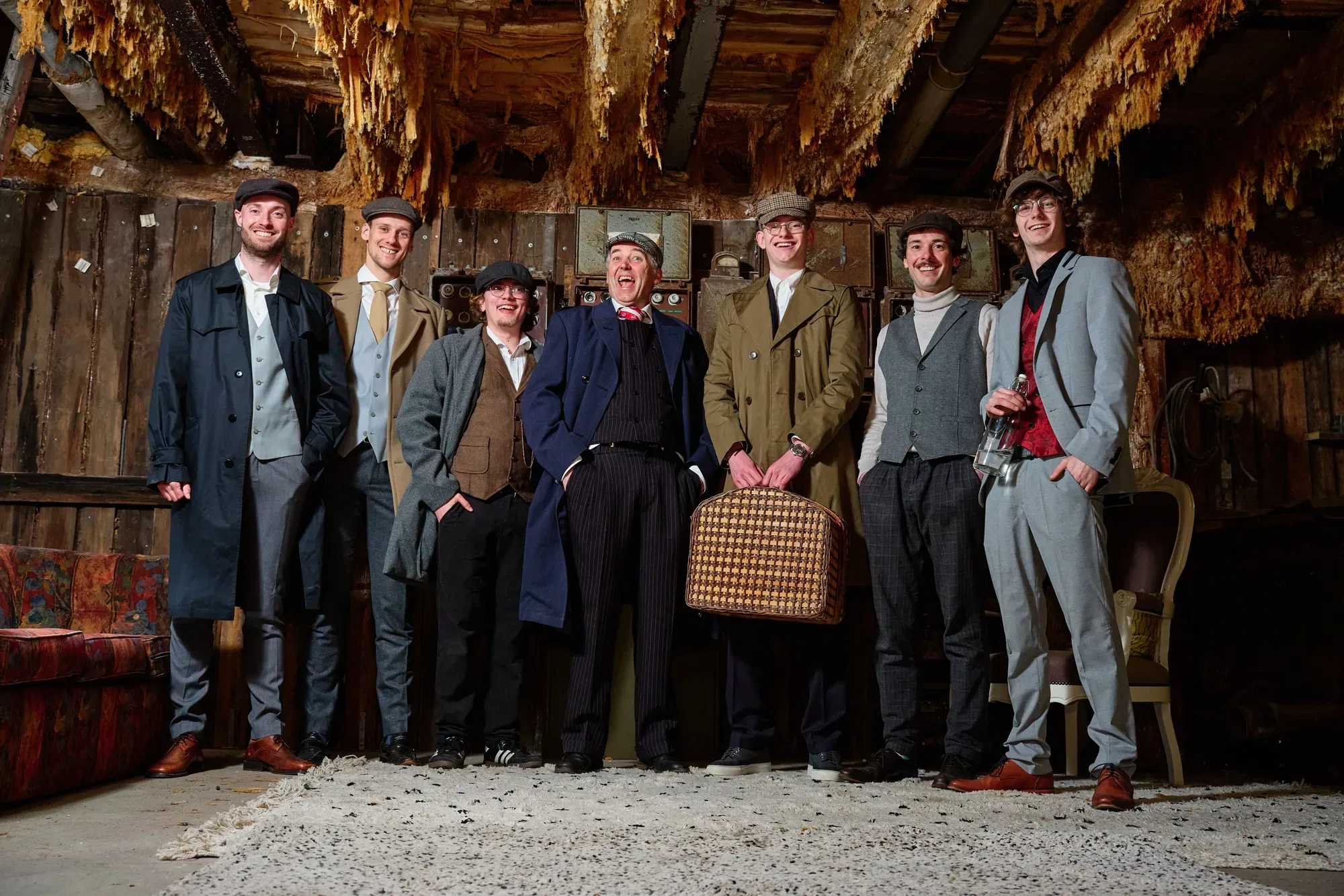 De mannen van de familie op een rij in pakken met petten in Peaky Blinders-stijl