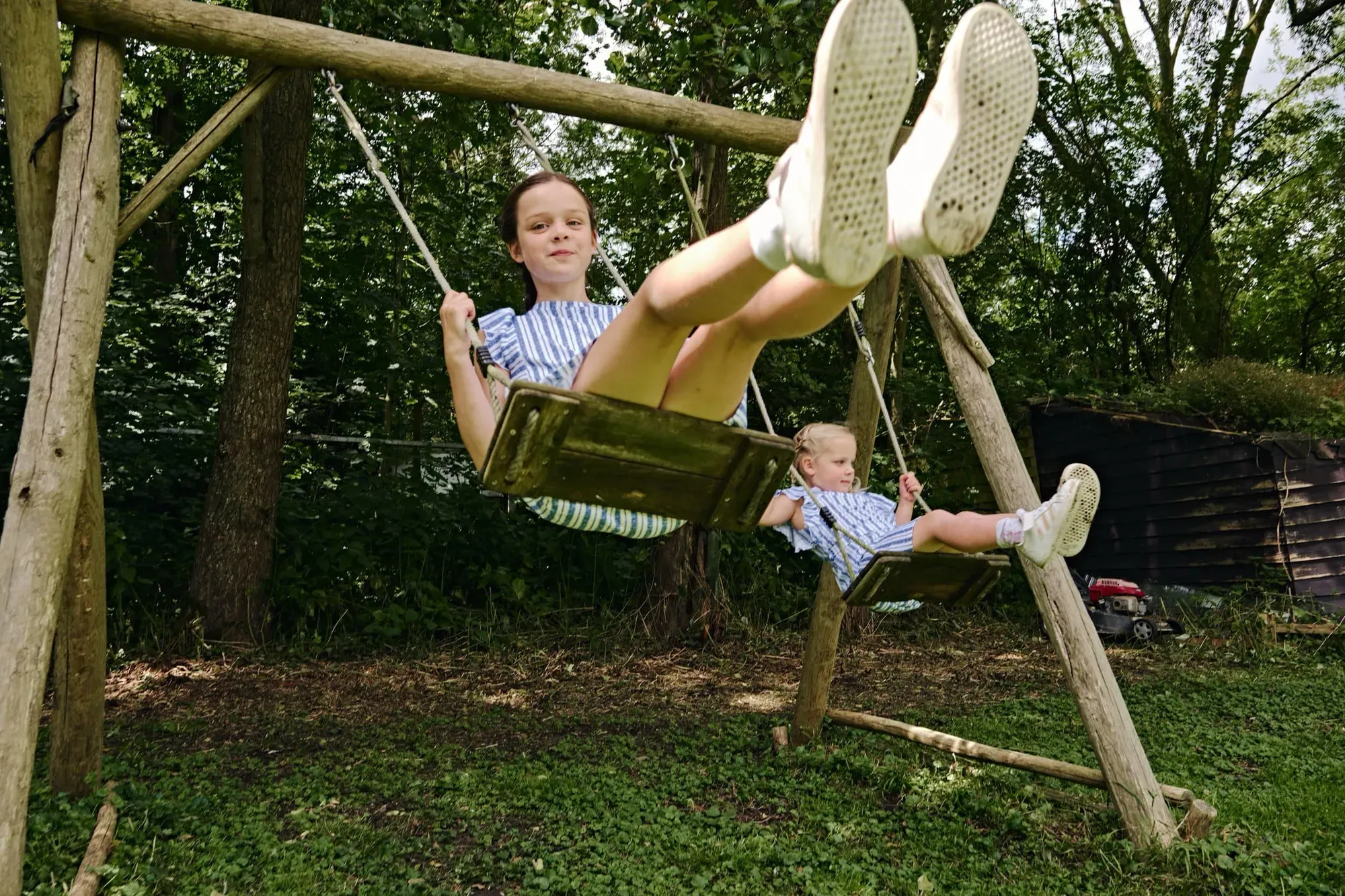 Twee jongens spelen op een houten schommel in de tuin