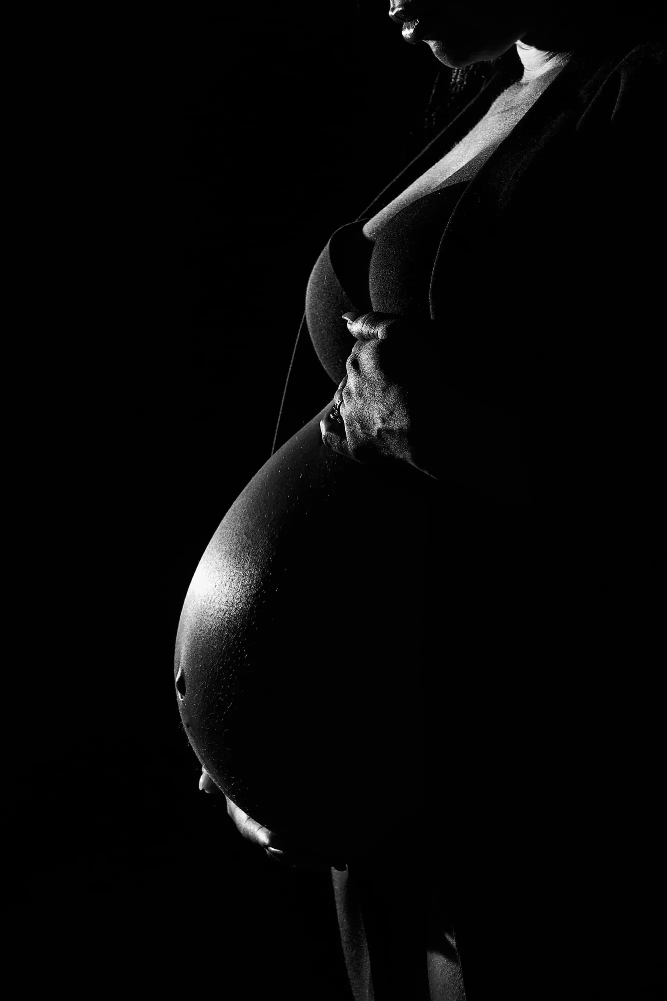 Silhouet van een zwangere vrouw tegen een zwarte achtergrond