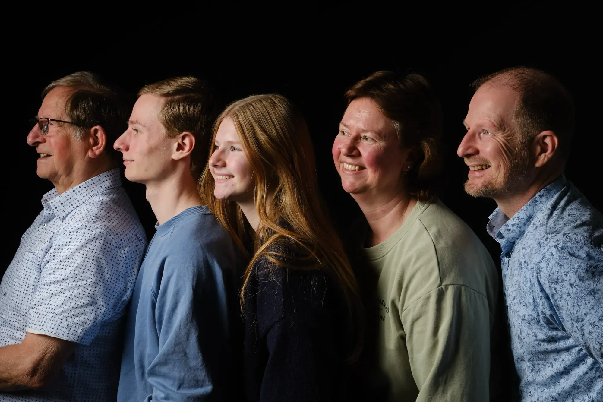 Familie staat in profiel achter elkaar voor een zwarte achtergrond