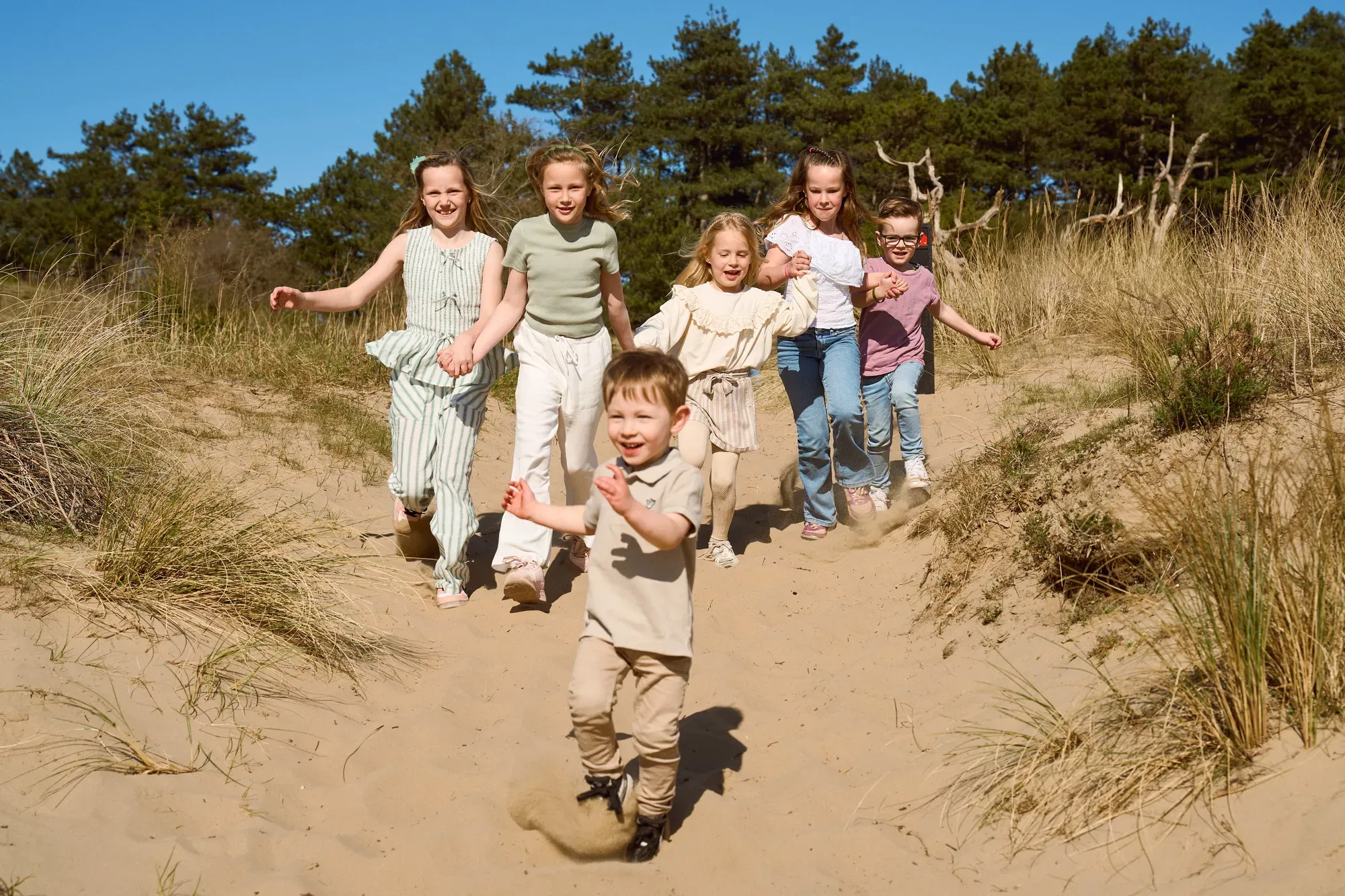Kinderen rennen lachend een zandduin af in de lente