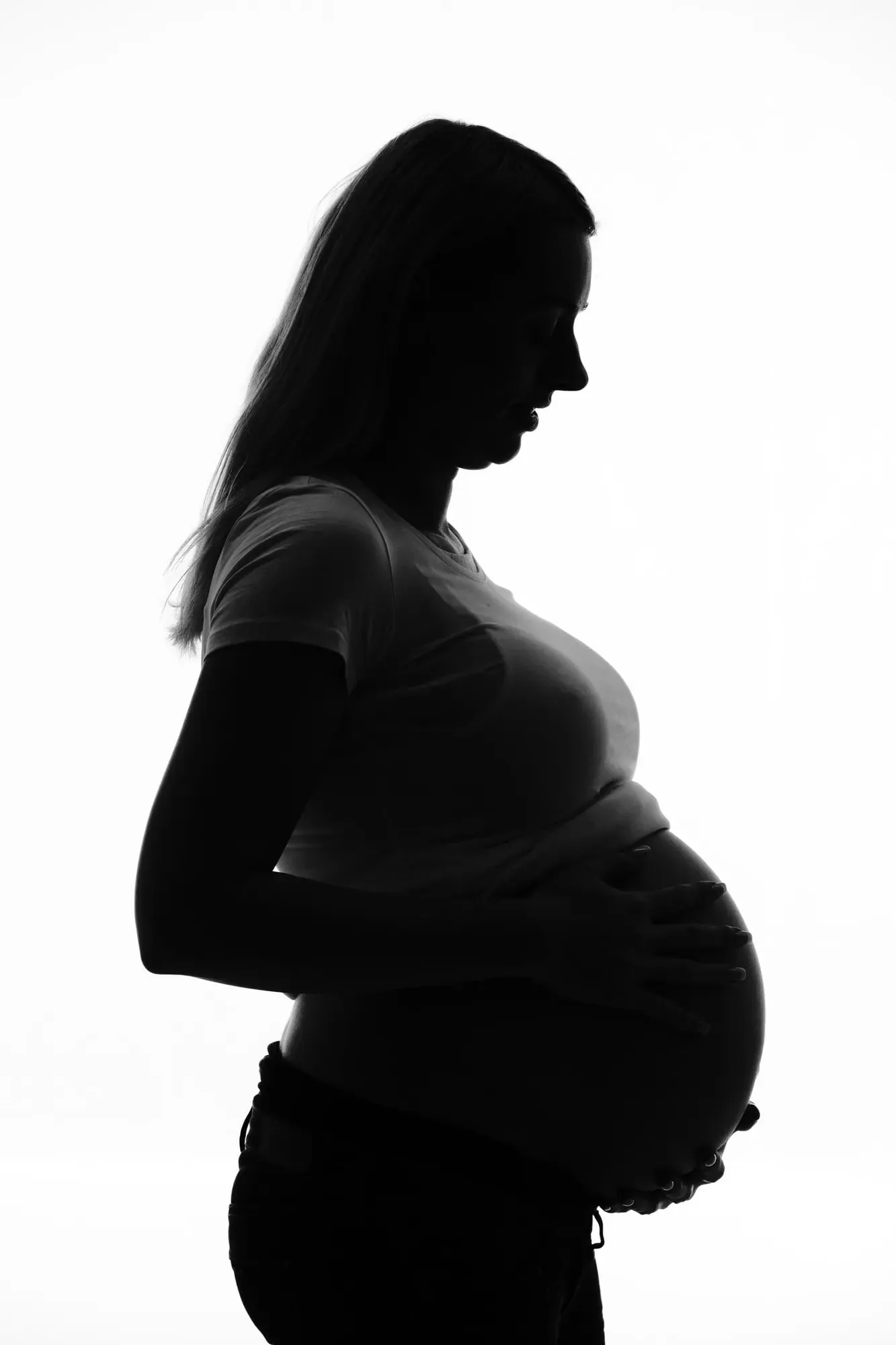 Silhouet van een zwangere vrouw tegen een witte achtergrond
