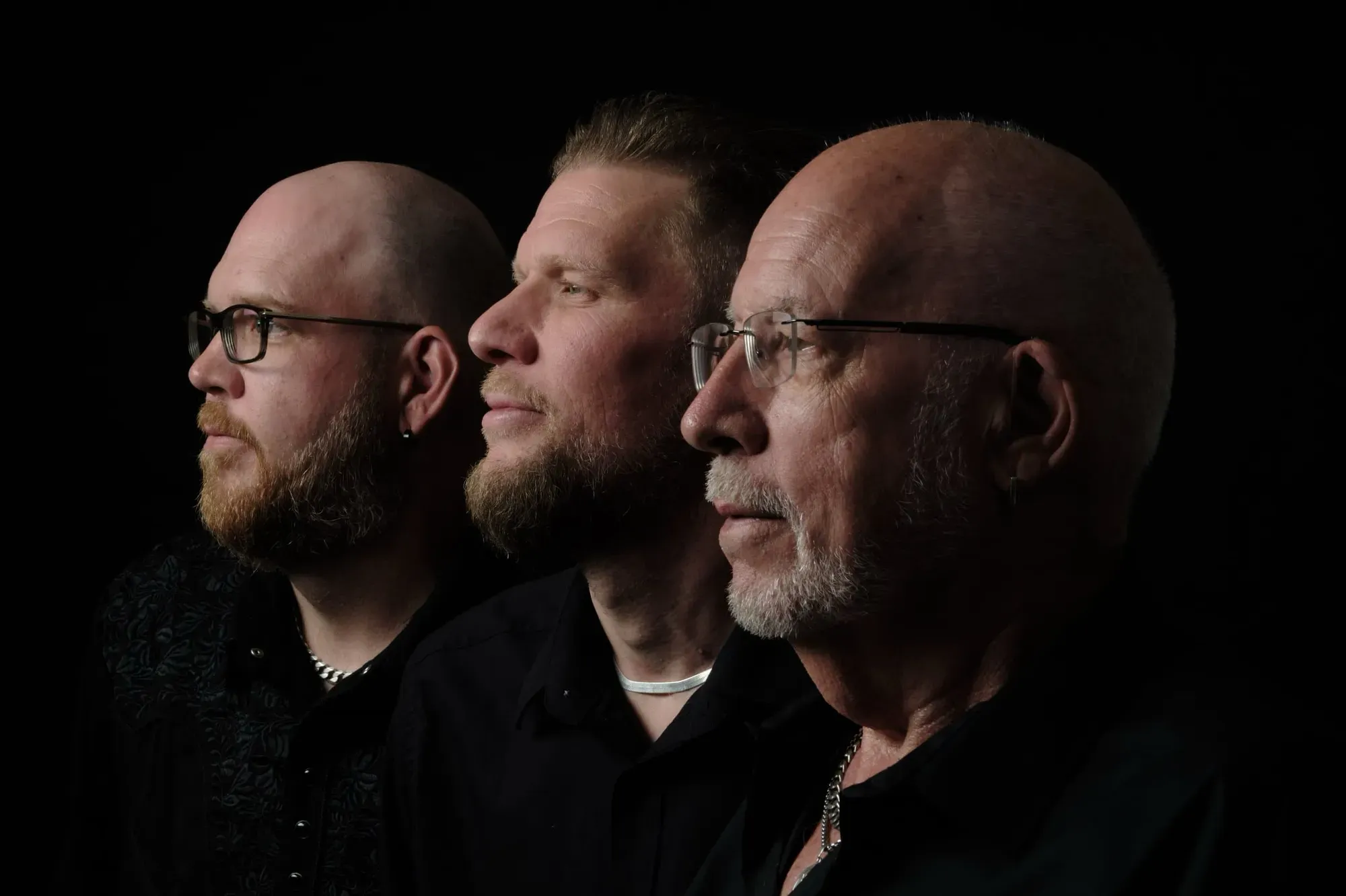 Drie mannen in profiel naast elkaar tegen een zwarte achtergrond