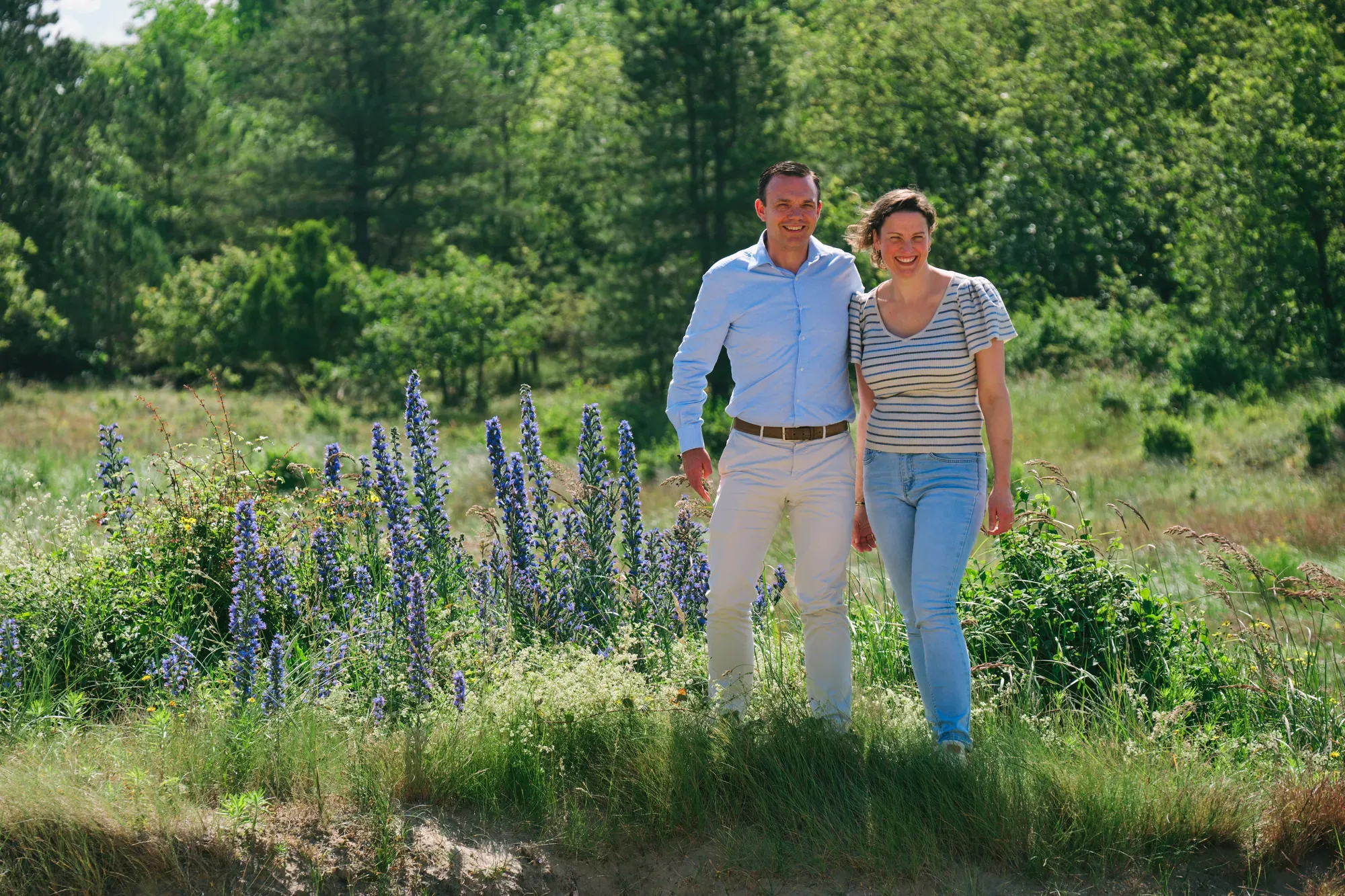 Stel staat tussen bloeiende paarse bloemen in de duinen in juni