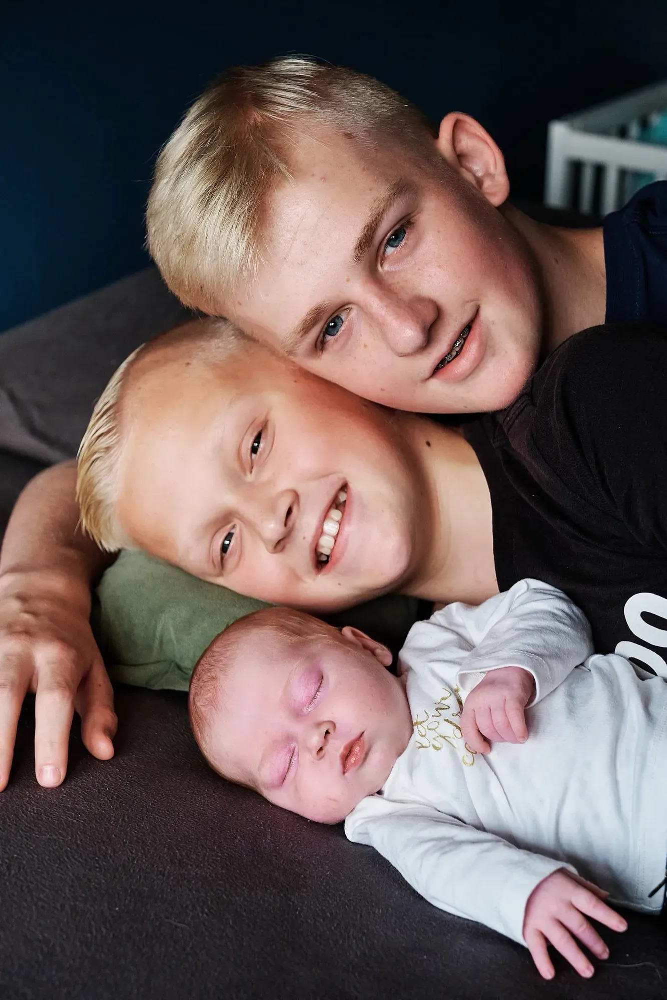 Twee grote broers liggen samen met de baby