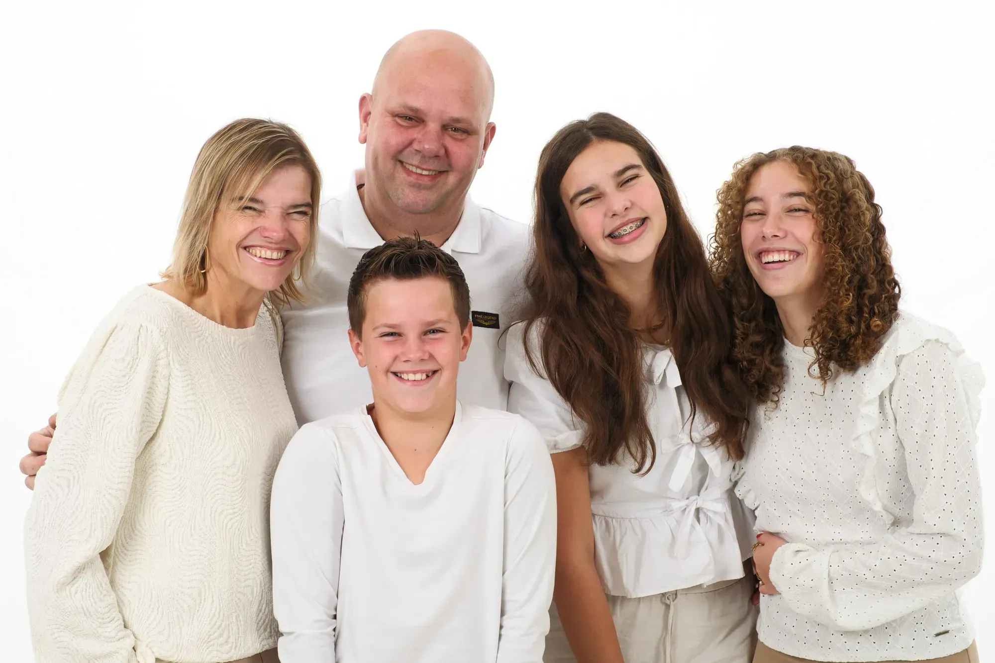 Familie in witte en crèmekleurige kleding staat dicht bij elkaar