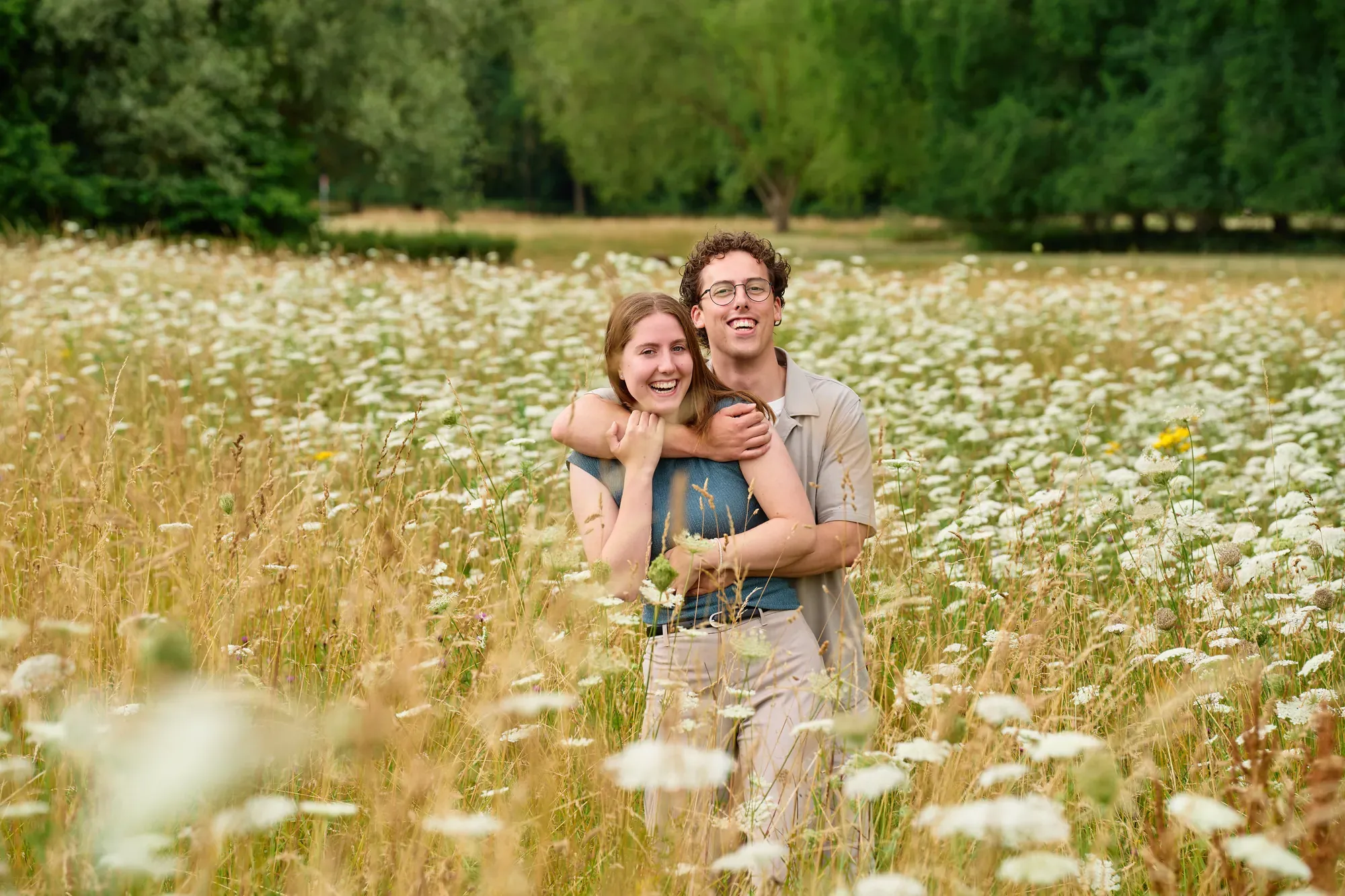 Stel omhelst elkaar tussen de wilde bloemen in het Westerpark in de zomer