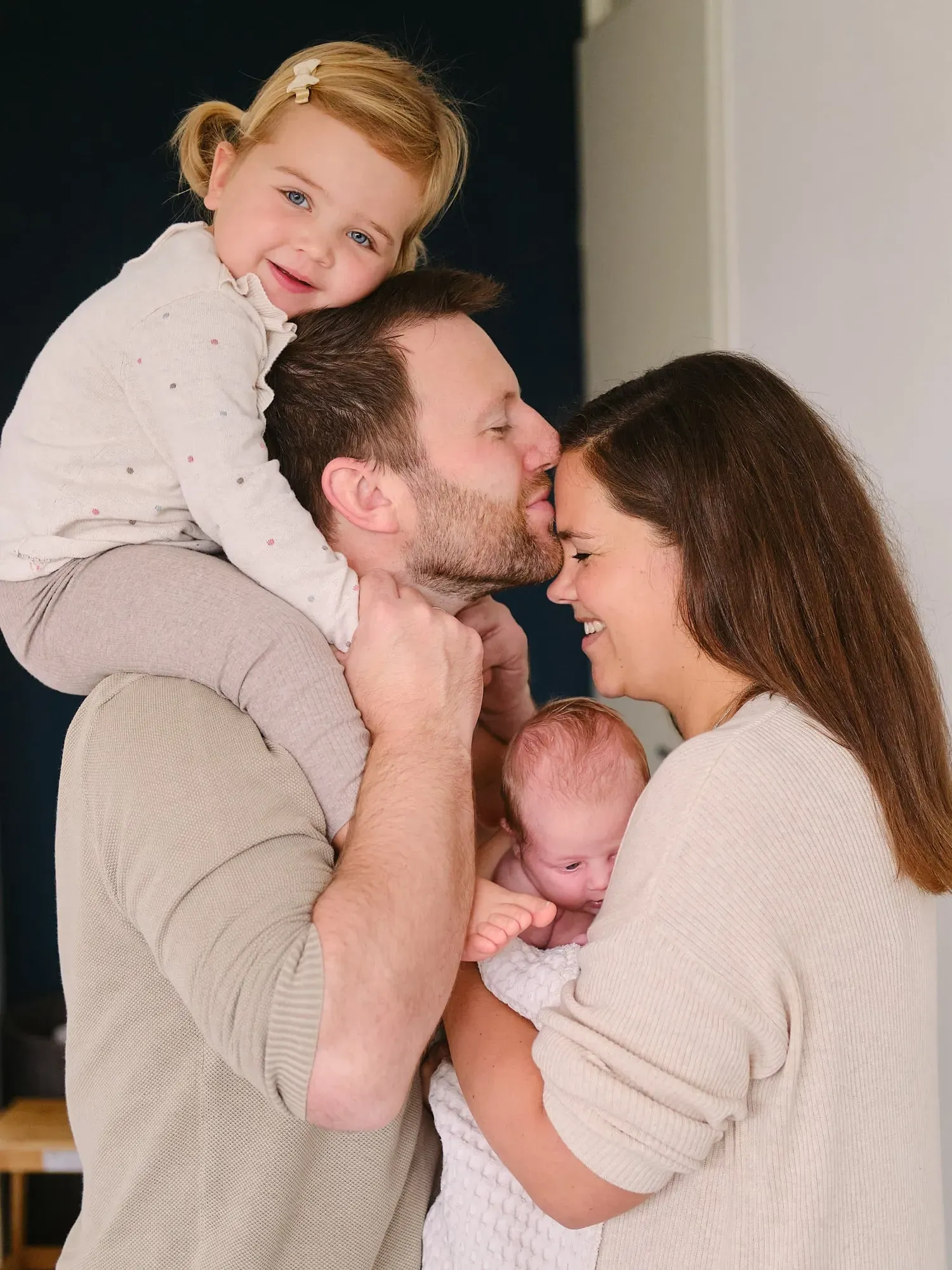 Dochter zit op papa’s schouders terwijl mama de baby vasthoudt