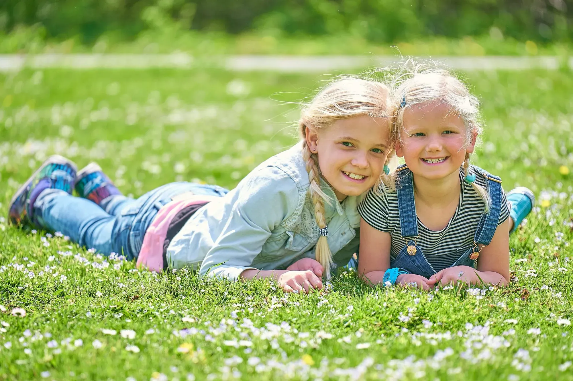 Twee zusjes liggen lachend in het gras