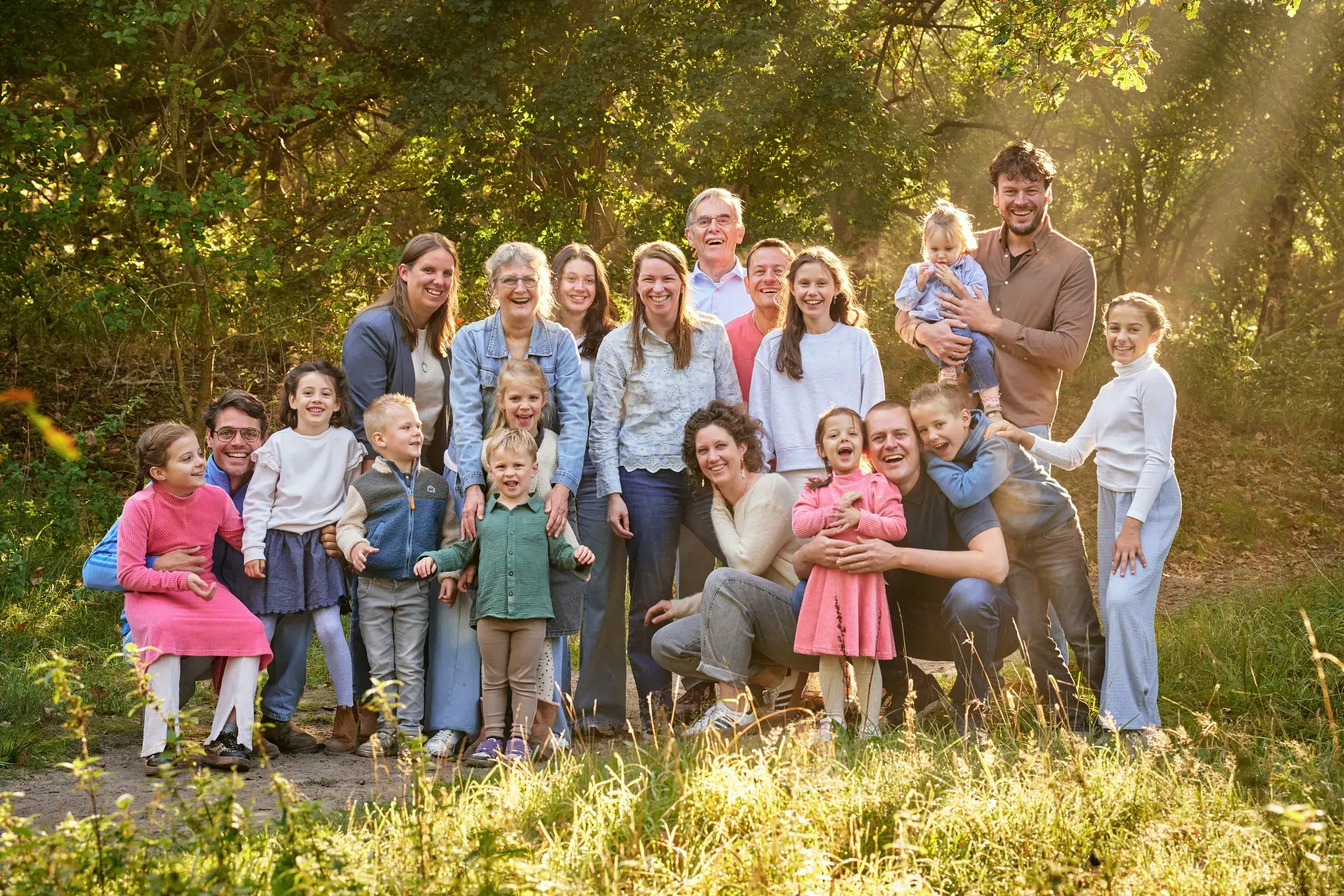 Grote familie in warm tegenlicht aan de bosrand op een septemberochtend