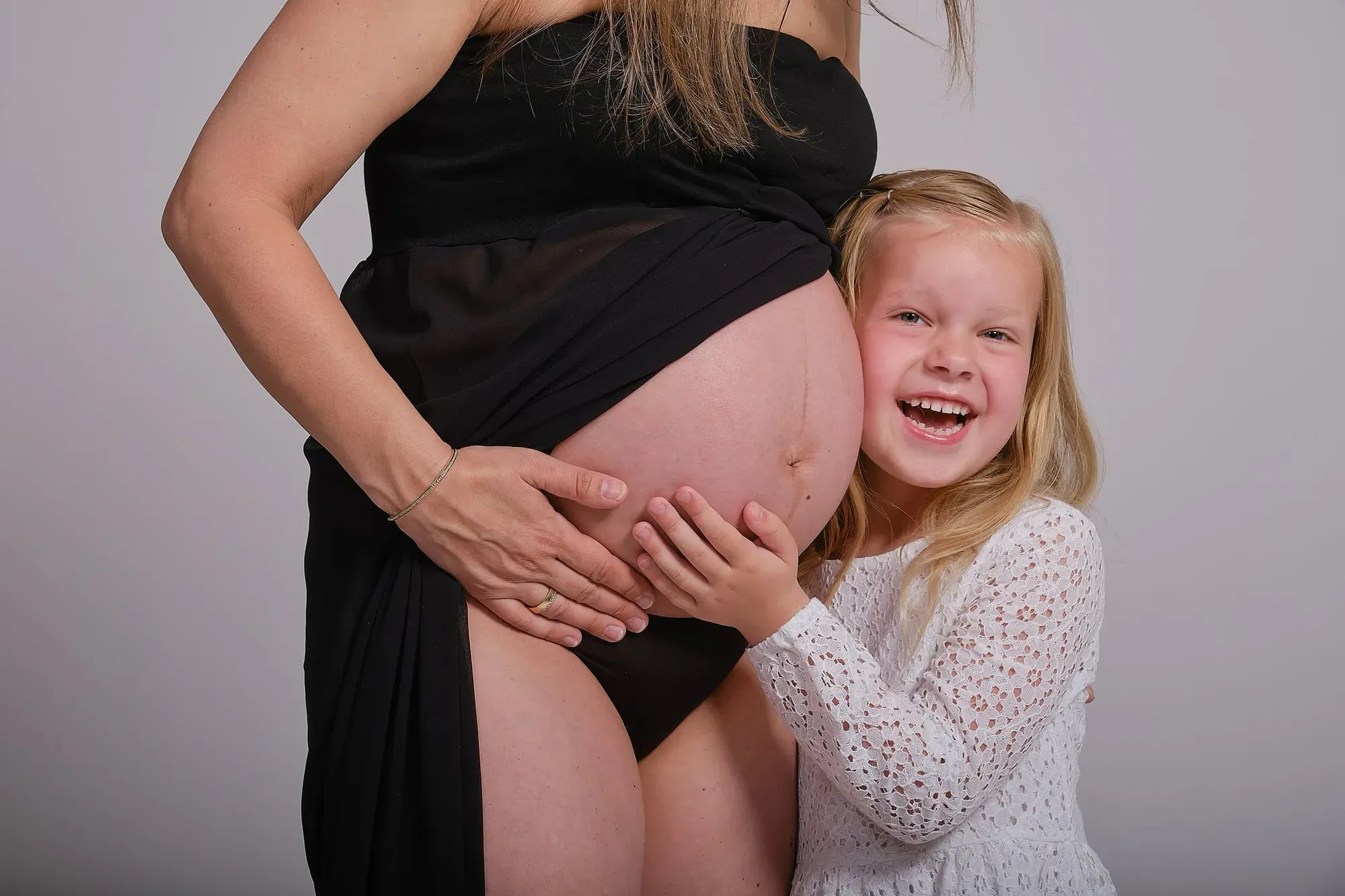 Zwangere moeder met haar dochter dicht bij de buik
