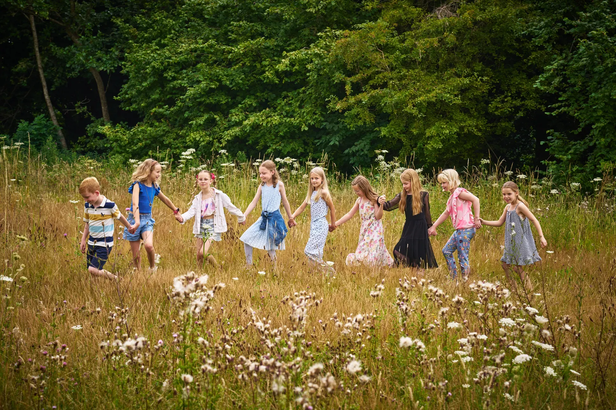 Rij kinderen rent hand in hand door de wilde bloemen in het Westerpark