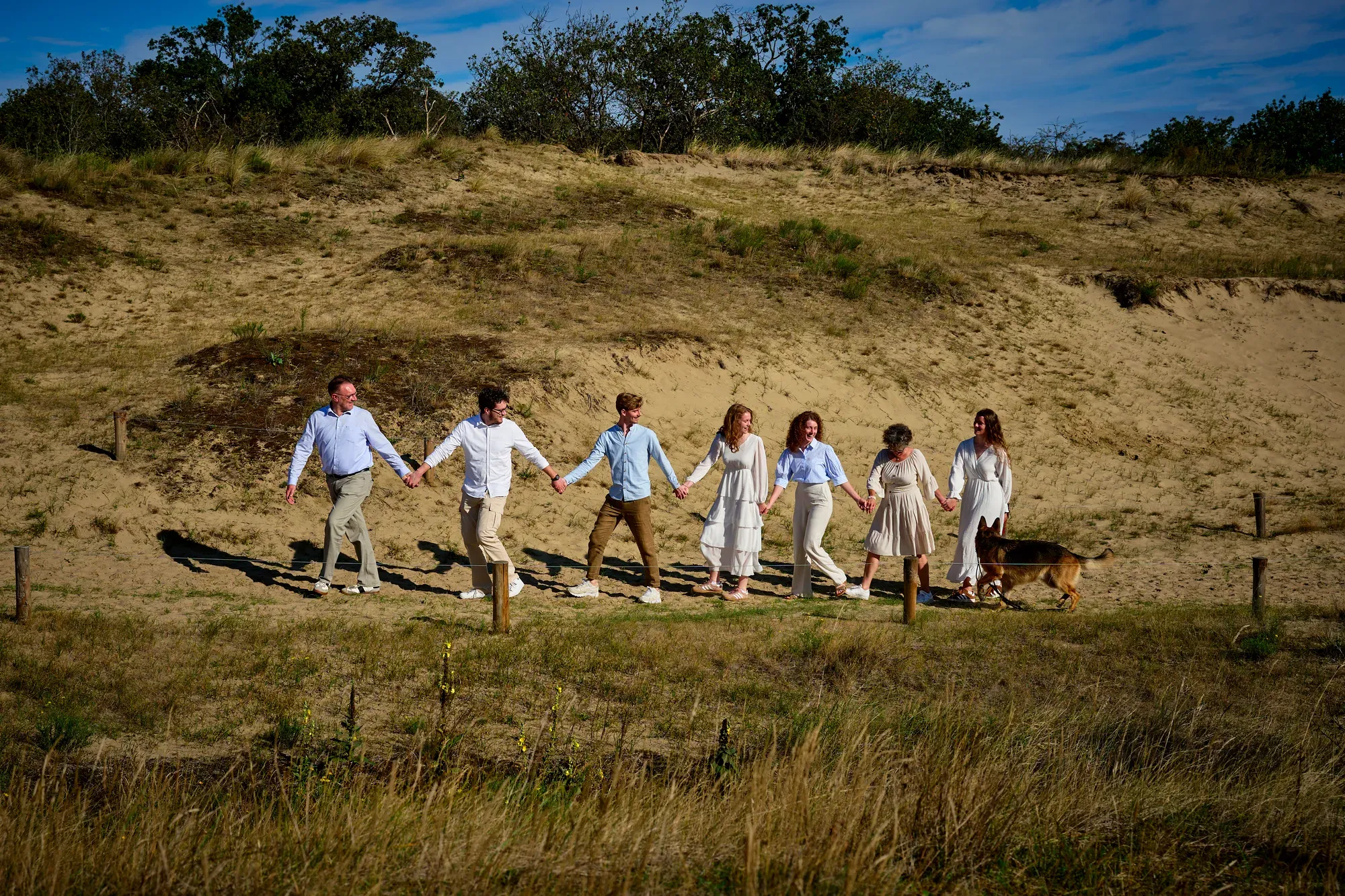 Familie loopt hand in hand door de vallei met helmgras