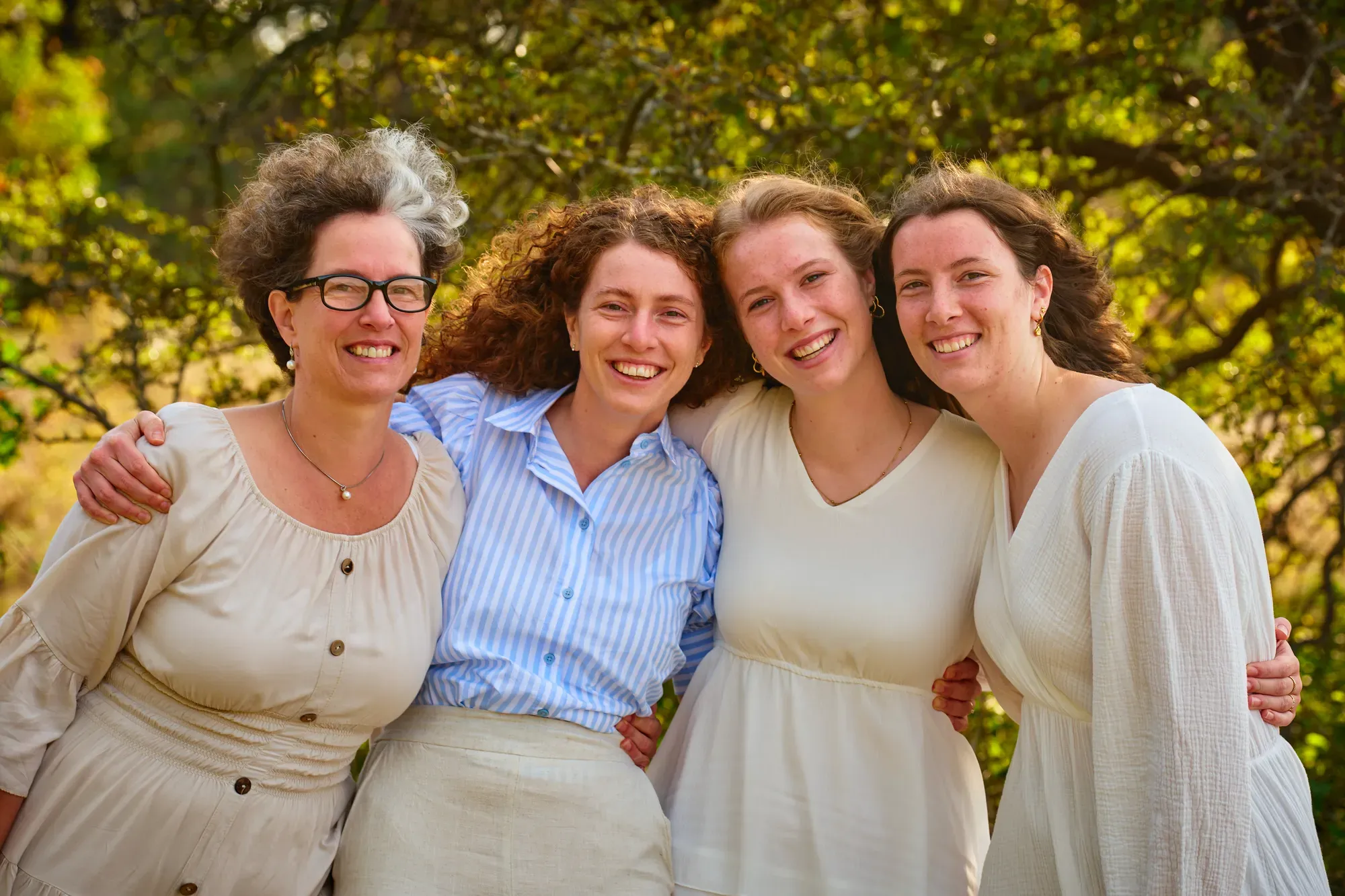 Vier vrouwen lachen samen in het warme zonlicht tussen het groen
