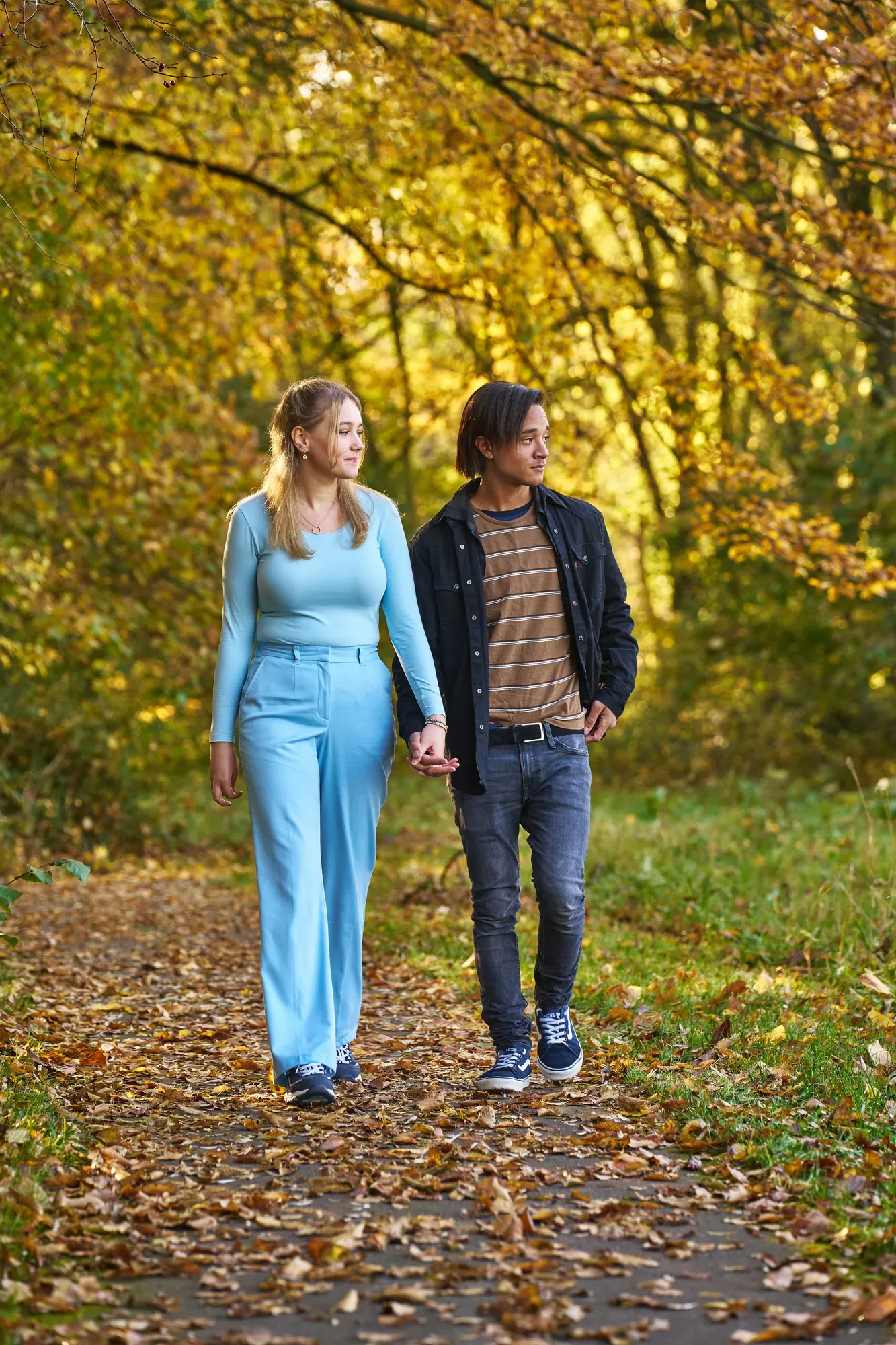Stel loopt hand in hand over een pad vol herfstbladeren in het Westerpark