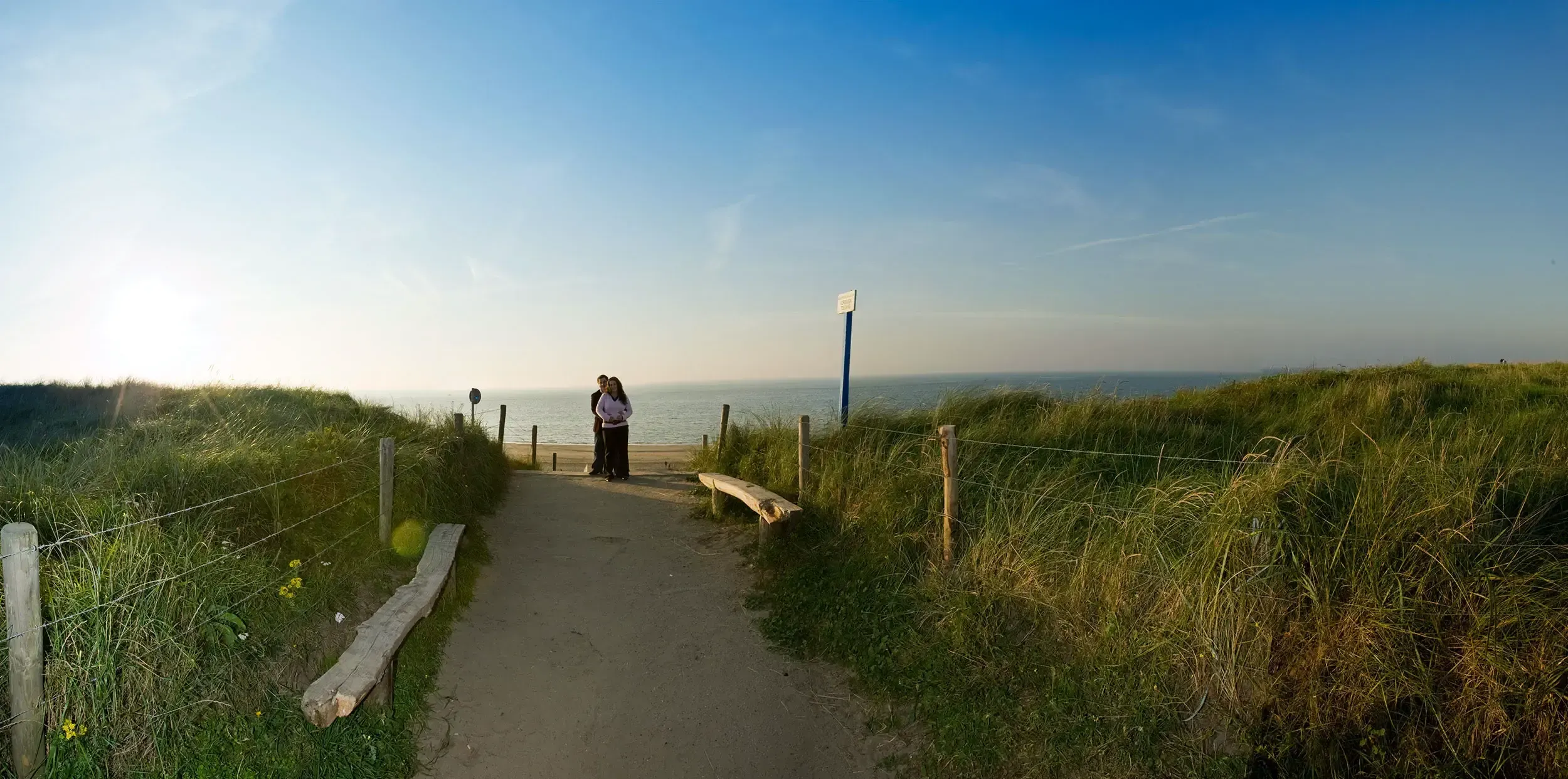 Panorama van het strand, waarbij de personen als klein detail in het brede landschap zijn opgenomen.