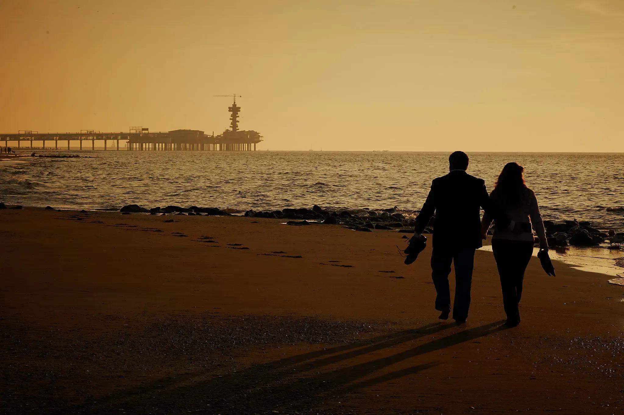 Silhouet op het strand met de Pier van Scheveningen op de achtergrond, in het laatste licht van de dag.