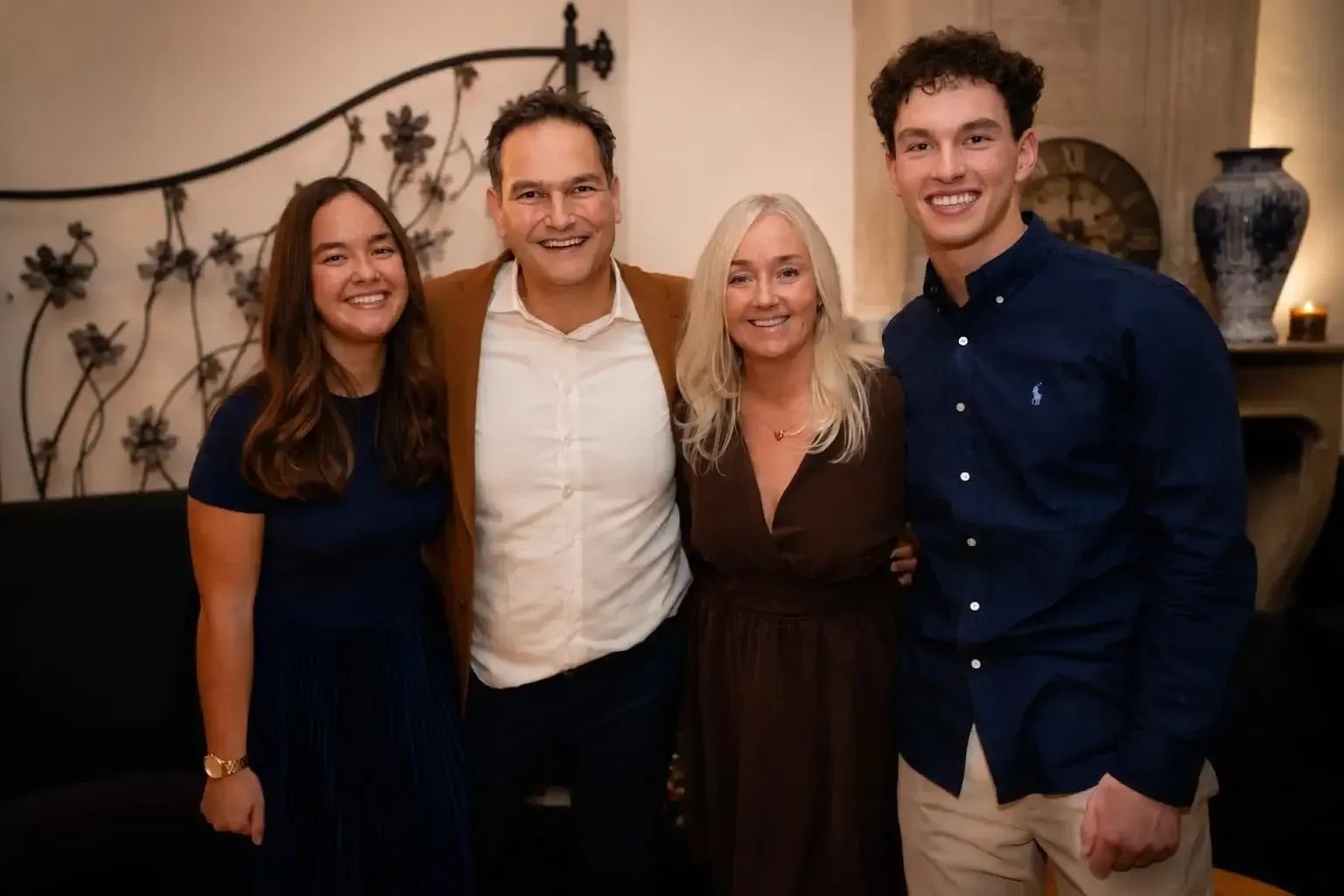 Vier mensen die glimlachend op een feestje poseren in een gezellige kamer.
